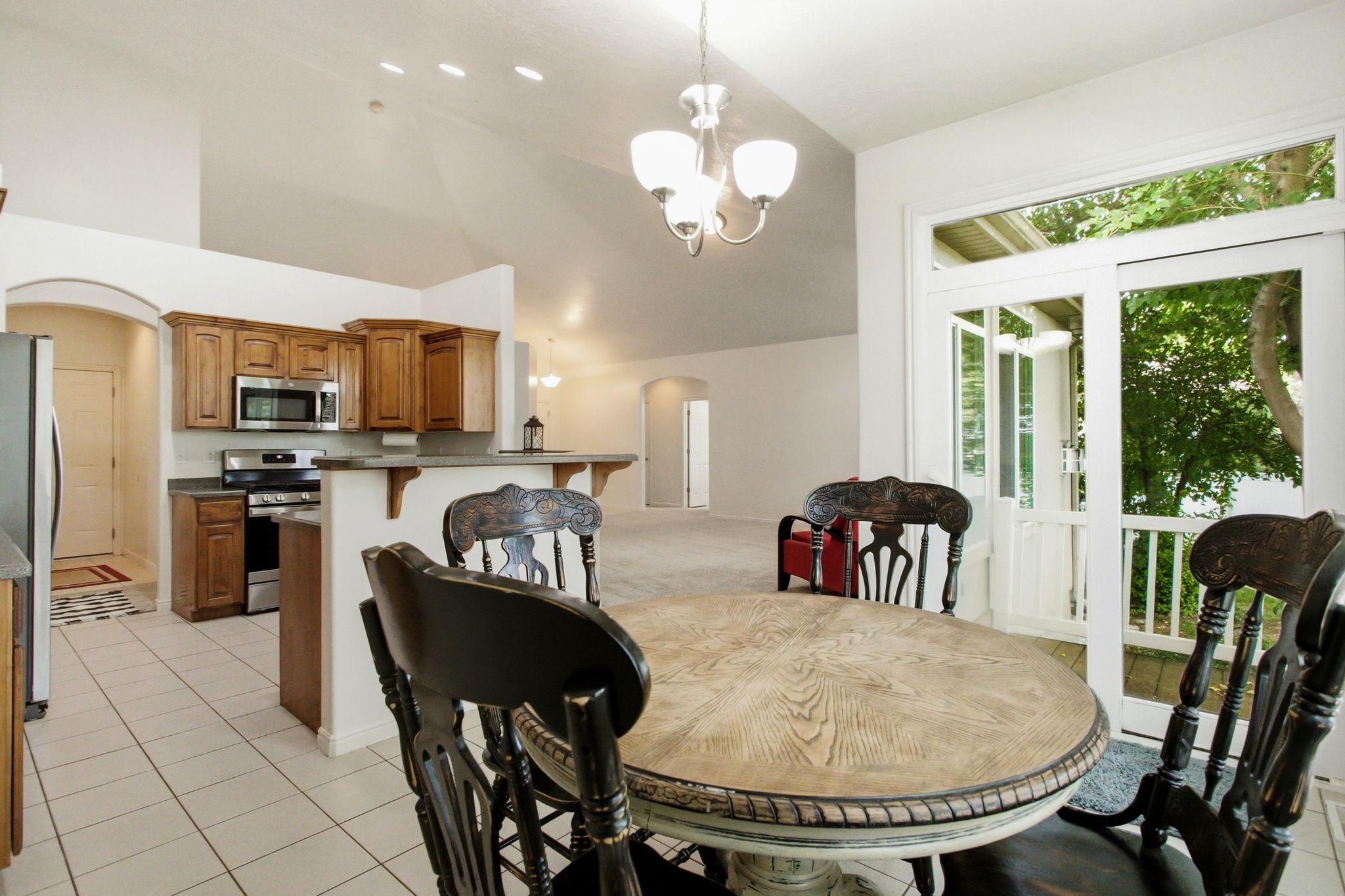 Kitchen with wood cabinetry, stainless steel appliances, and a breakfast bar, featuring tile flooring and vaulted ceilings