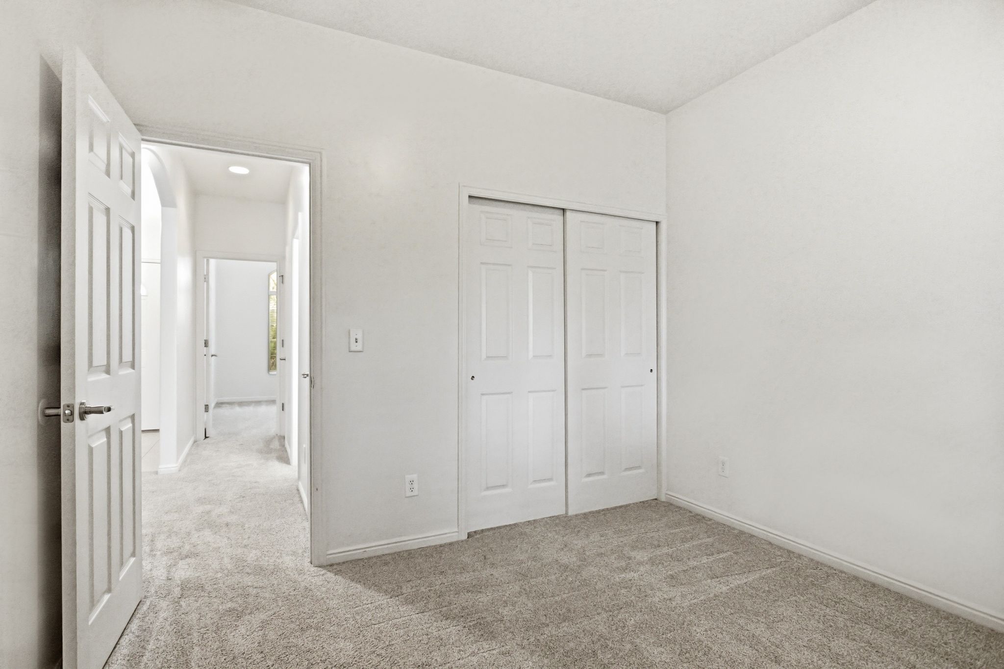Carpeted room with white walls, baseboards, and a bi-fold closet with panel doors