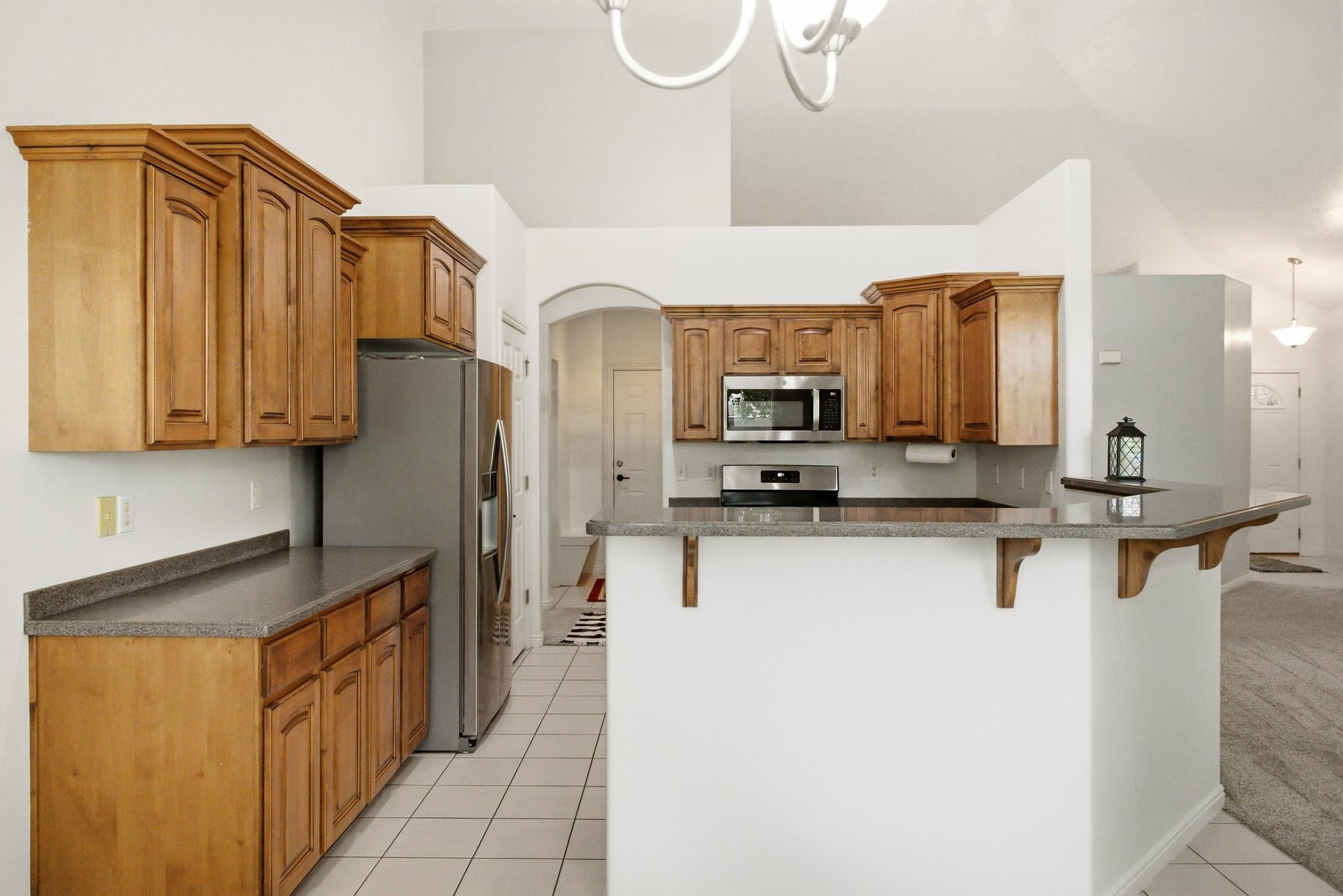 Kitchen featuring wood cabinetry, stainless steel appliances, speckled countertops, and a breakfast bar