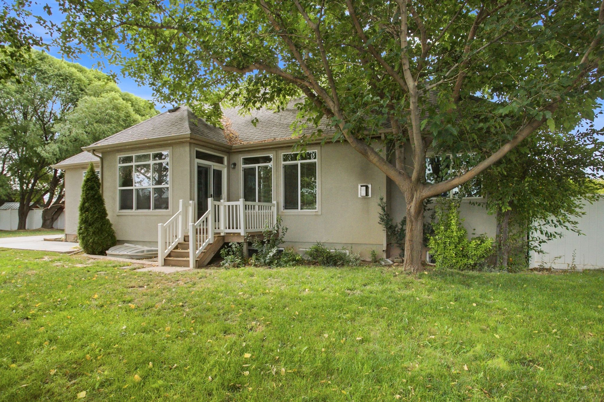 Rear exterior featuring multiple windows, a sunroom, and a wooden deck with white railings