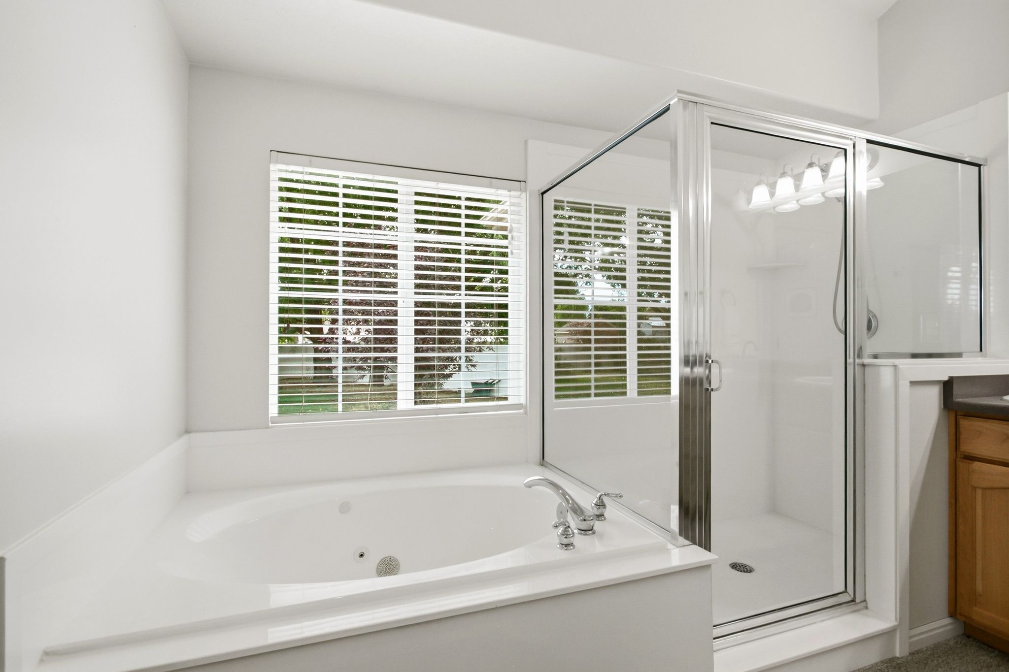 Modern bathroom featuring a built-in soaking tub, separate glass-enclosed shower, chrome fixtures, and a window with blinds