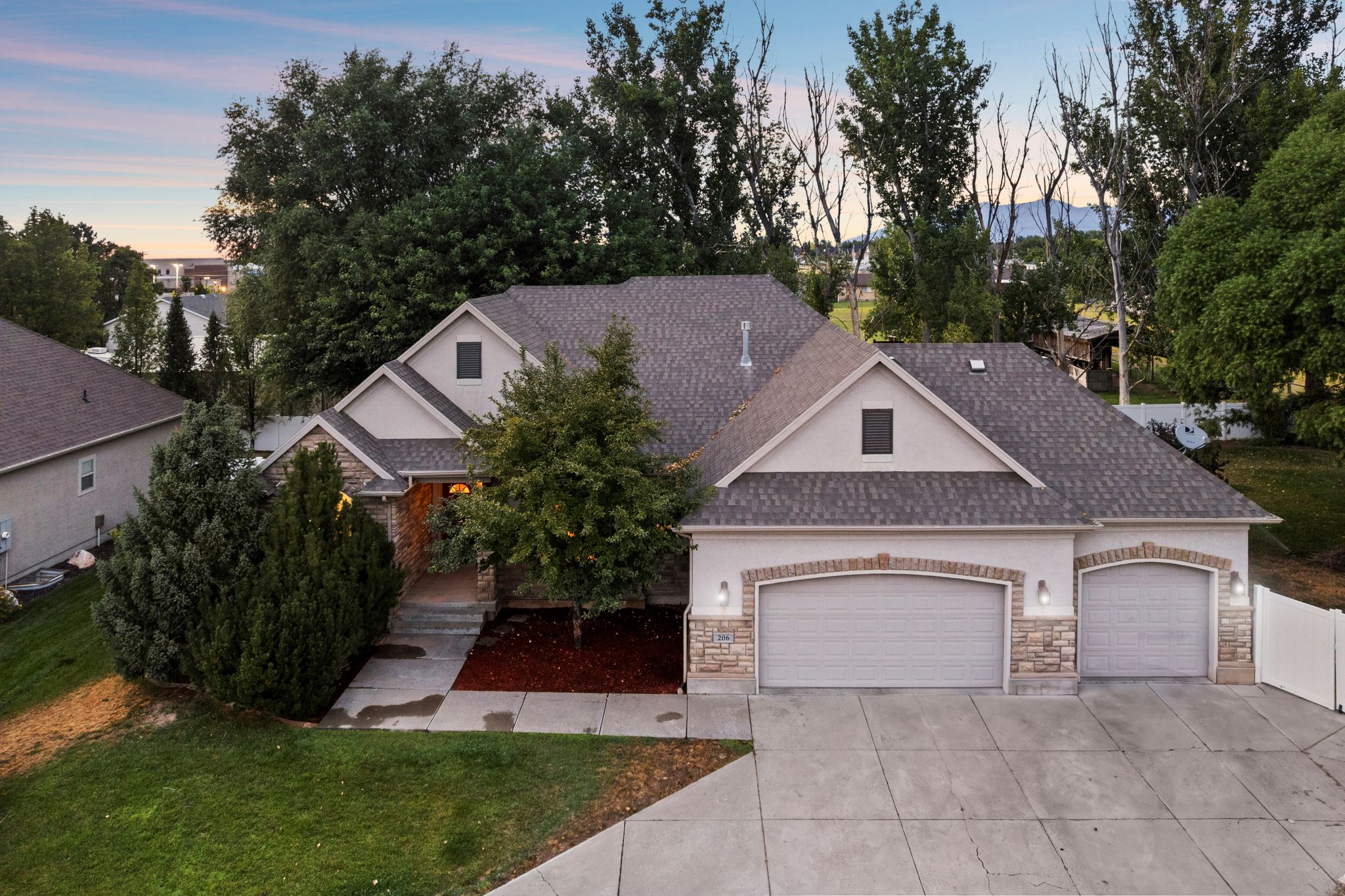 Gabled property exterior featuring a two-car and single-car garage, stone veneer accents, and a concrete driveway