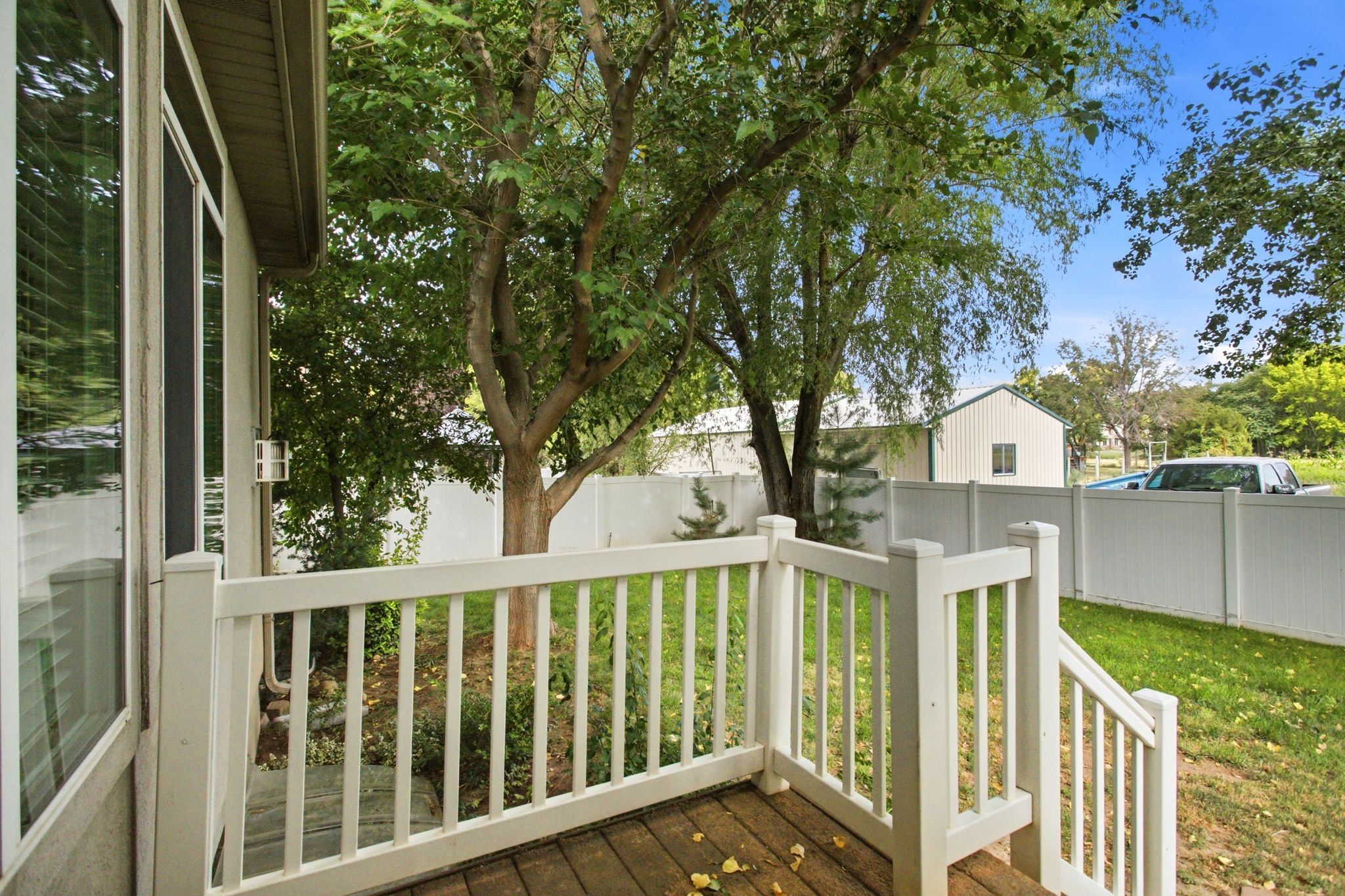 Outdoor deck with wood-finish flooring, white railing, and steps down to a green lawn