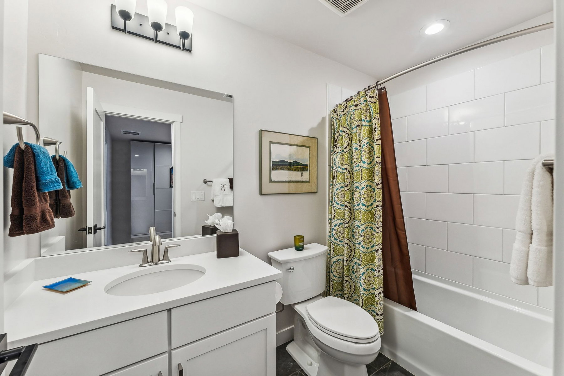 Bathroom featuring a white vanity with an integrated sink, brushed nickel faucet, and a rectangular mirror