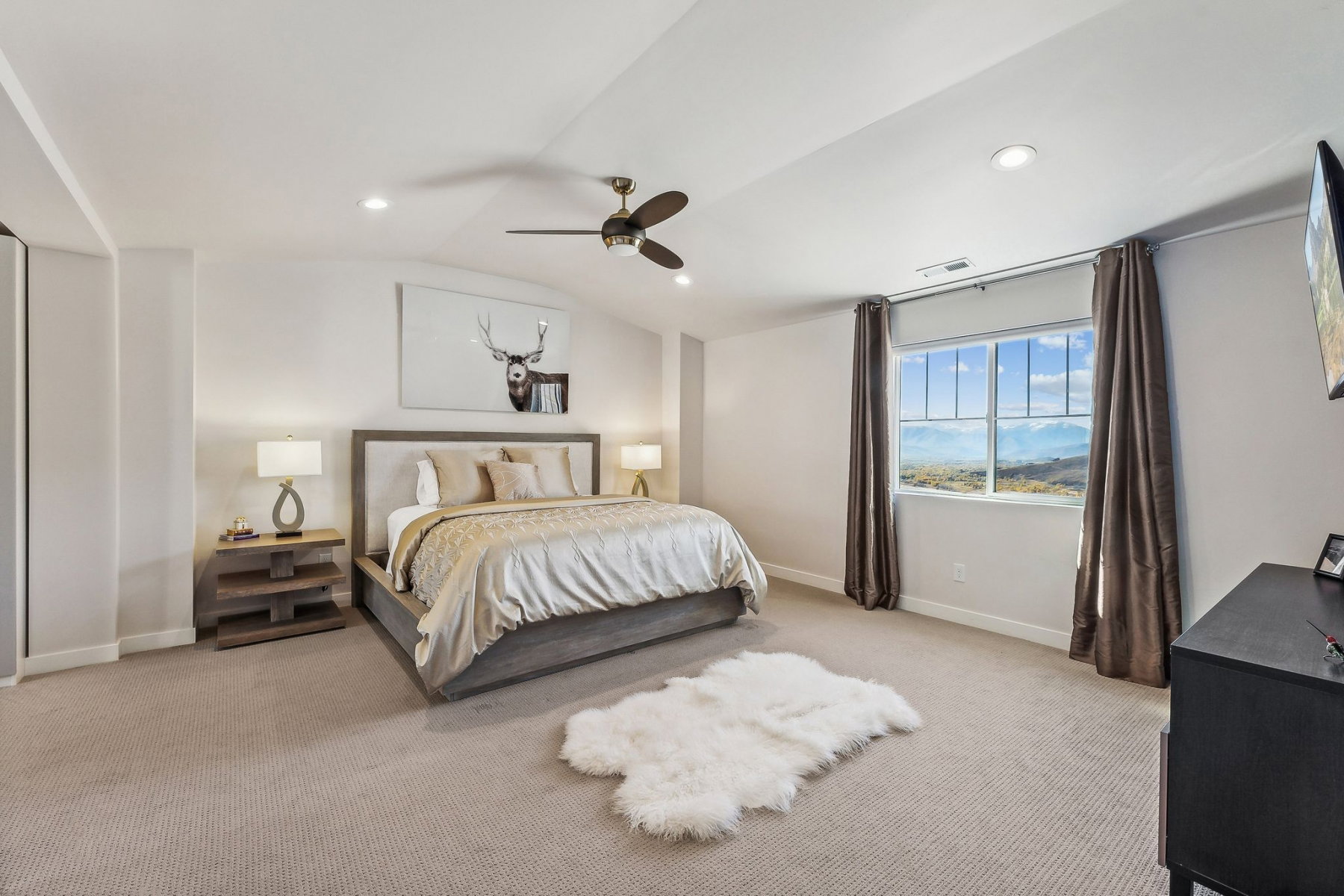 Spacious room featuring a large window with mountain scenery, sloped ceiling, recessed lighting, and a ceiling fan