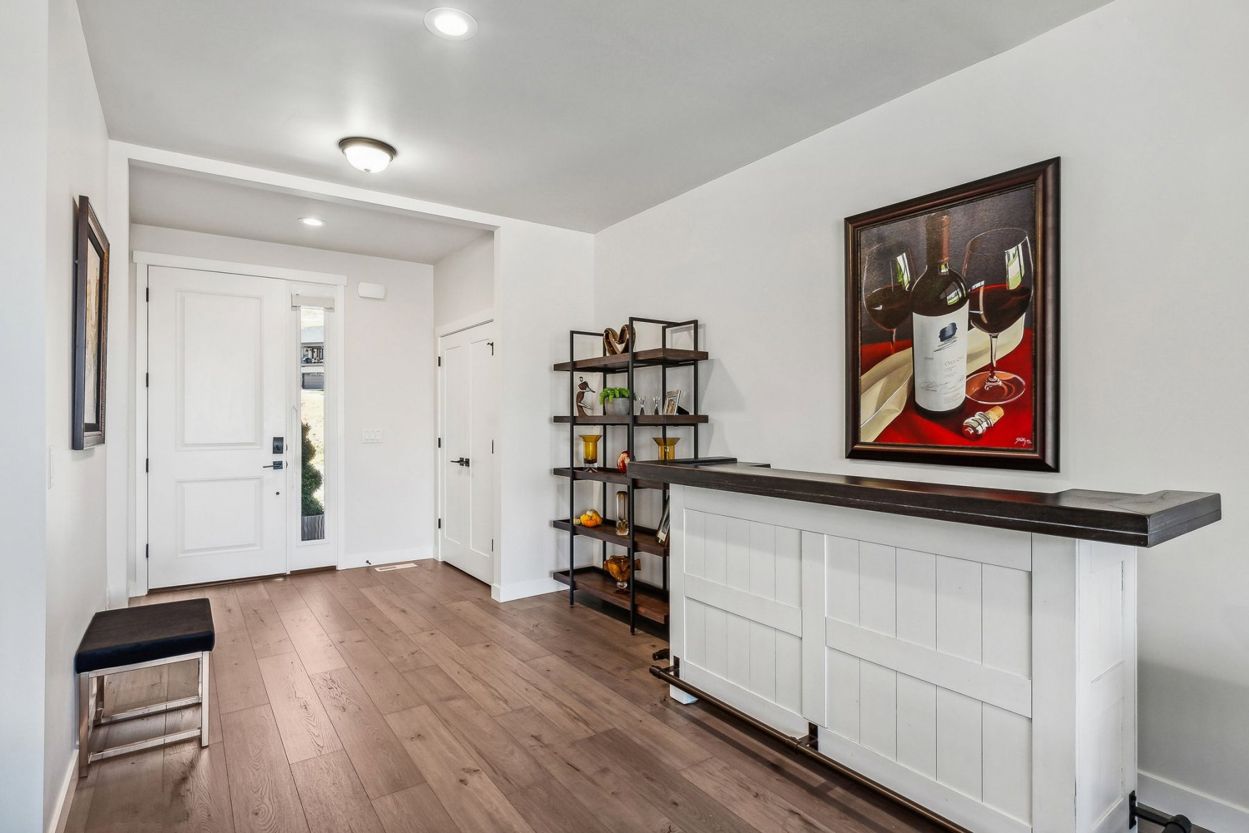Entryway featuring wood-finish flooring, a white paneled front door with side light, recessed lighting, and a built-in bar with a dark countertop and white paneled base