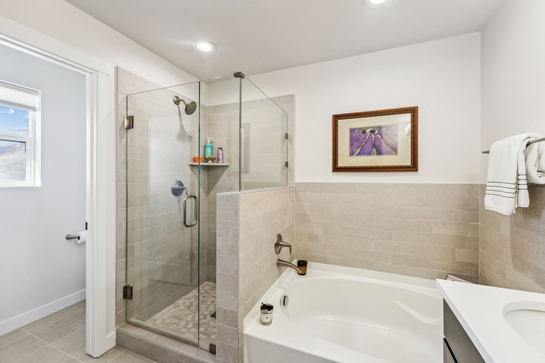 Bathroom featuring a glass-enclosed shower with pebble-tile flooring, a built-in shower niche, and a separate soaking tub with tile surround