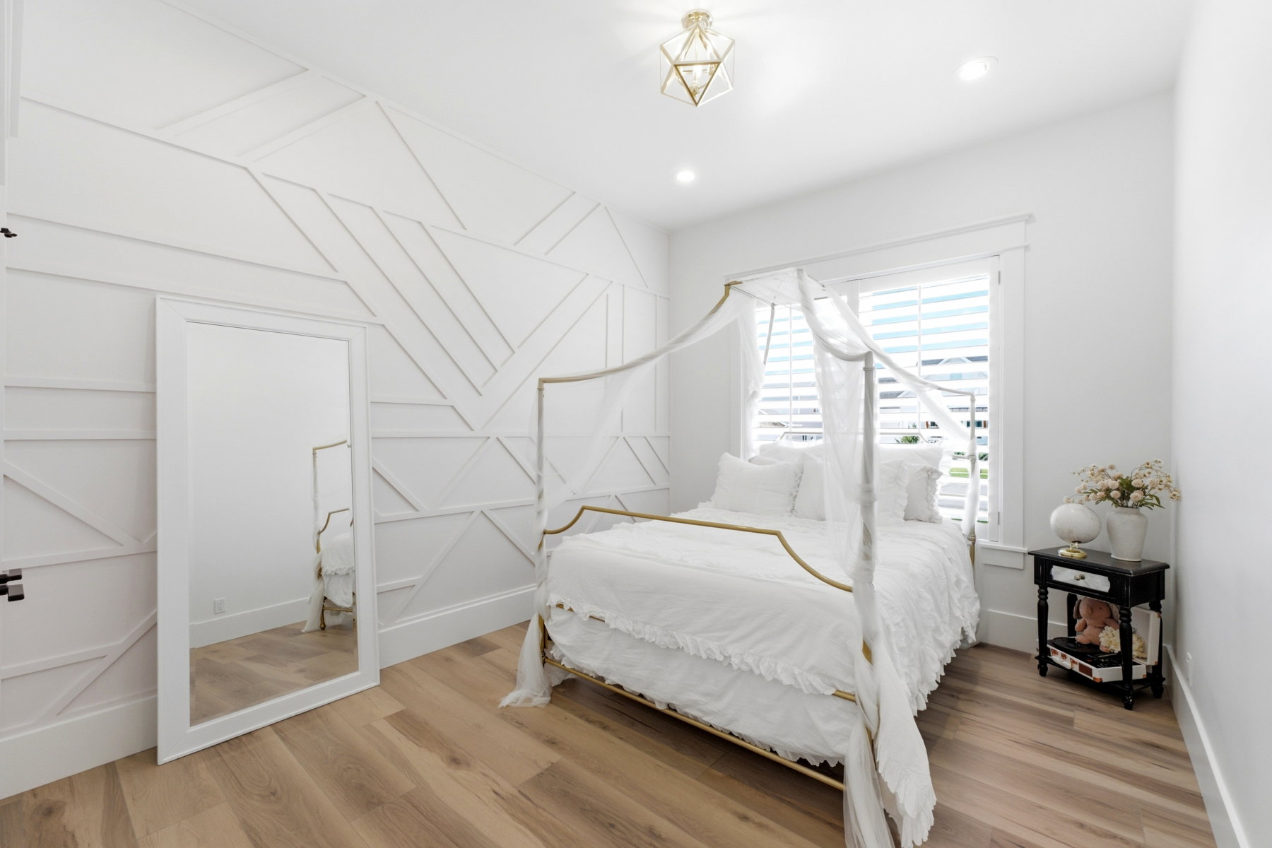 Accent wall featuring geometric paneling, wood-finish flooring, recessed lighting, and a window with plantation shutters