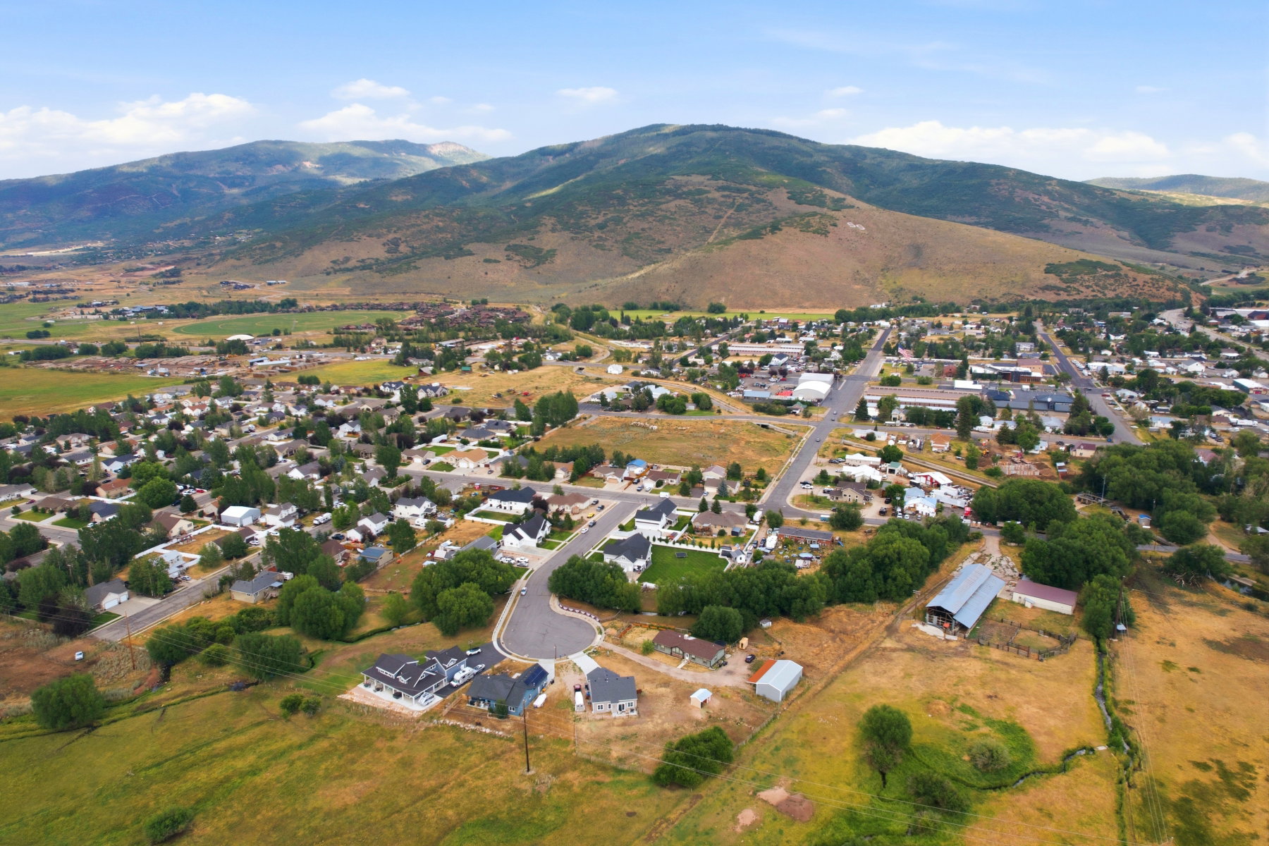 Expansive aerial perspective showcasing a residential community nestled at the base of a verdant mountain range