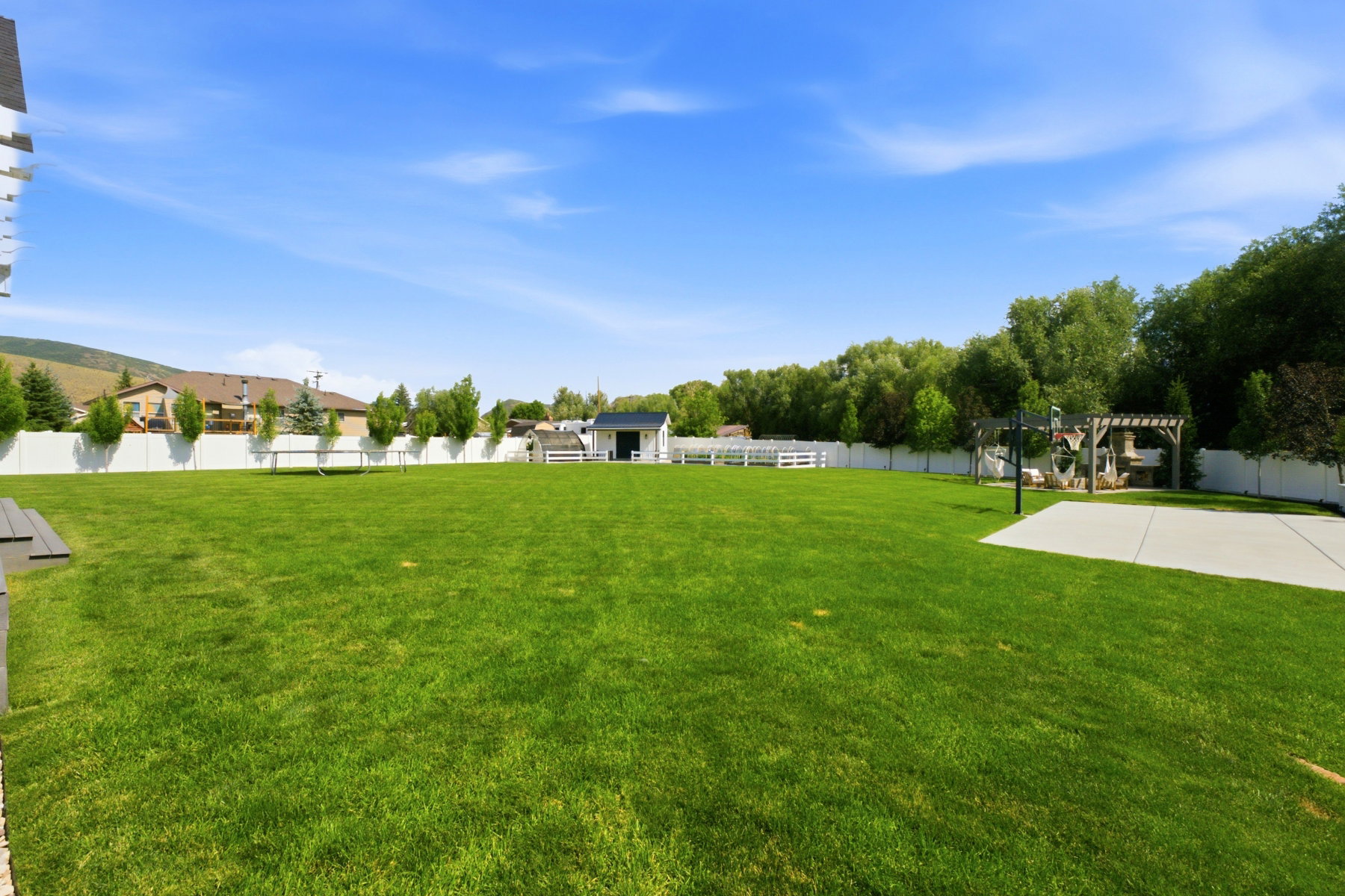 Expansive green lawn with a white privacy fence