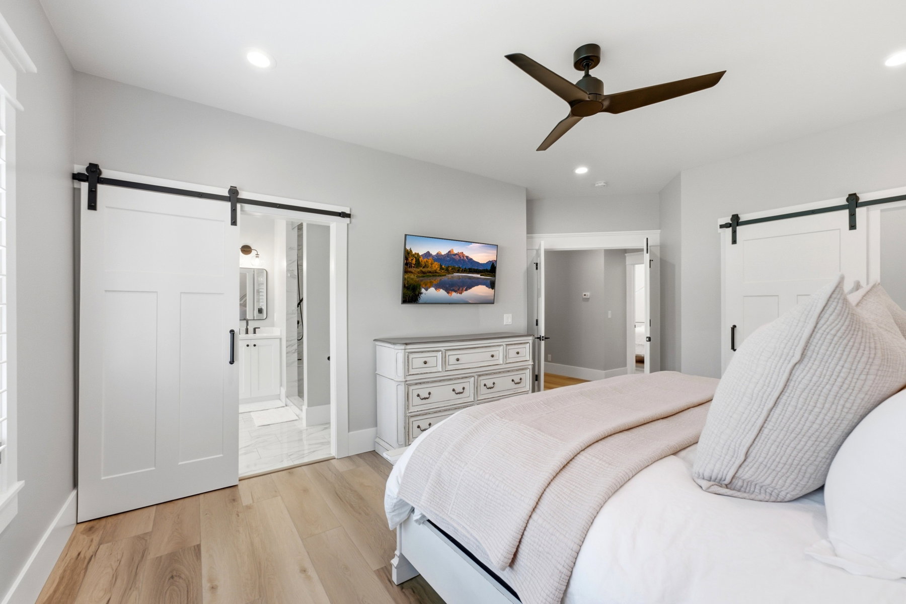 Interior room featuring wood-finish flooring, two barn-style doors with black hardware, a ceiling fan, and recessed lighting