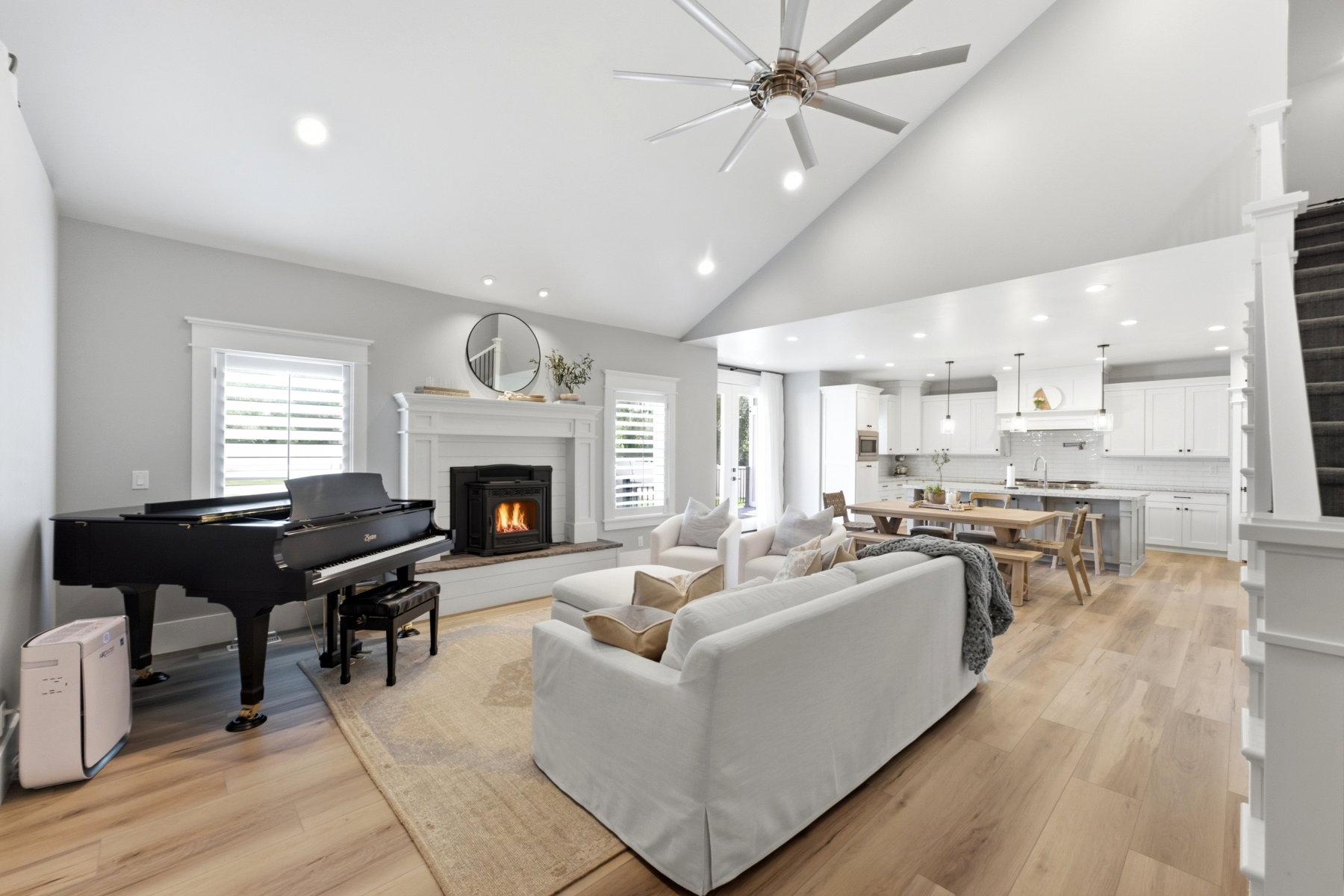 Open-concept living area with vaulted ceilings, a fireplace featuring a white mantel, and wood-finish flooring