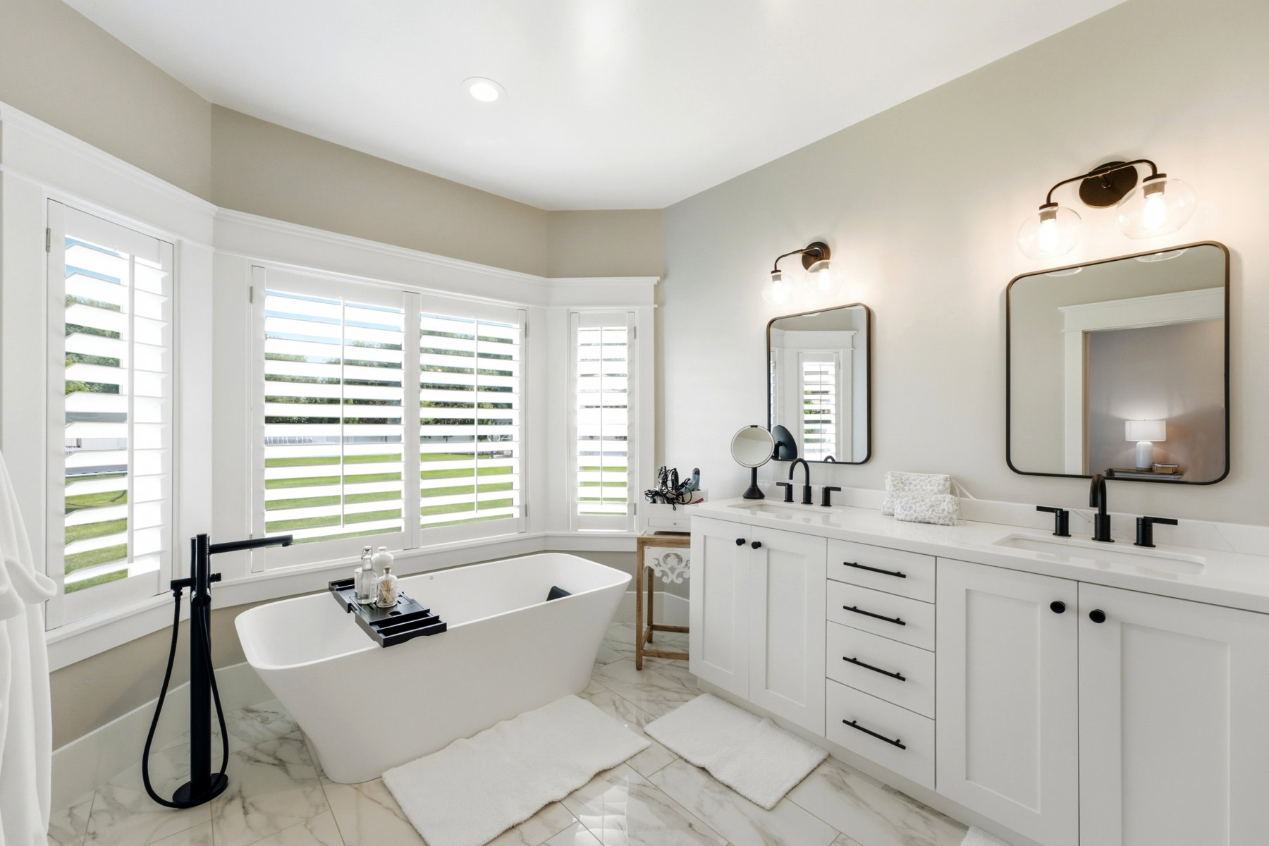 Freestanding soaking tub with a floor-mounted matte black faucet, surrounded by a bay window with plantation shutters