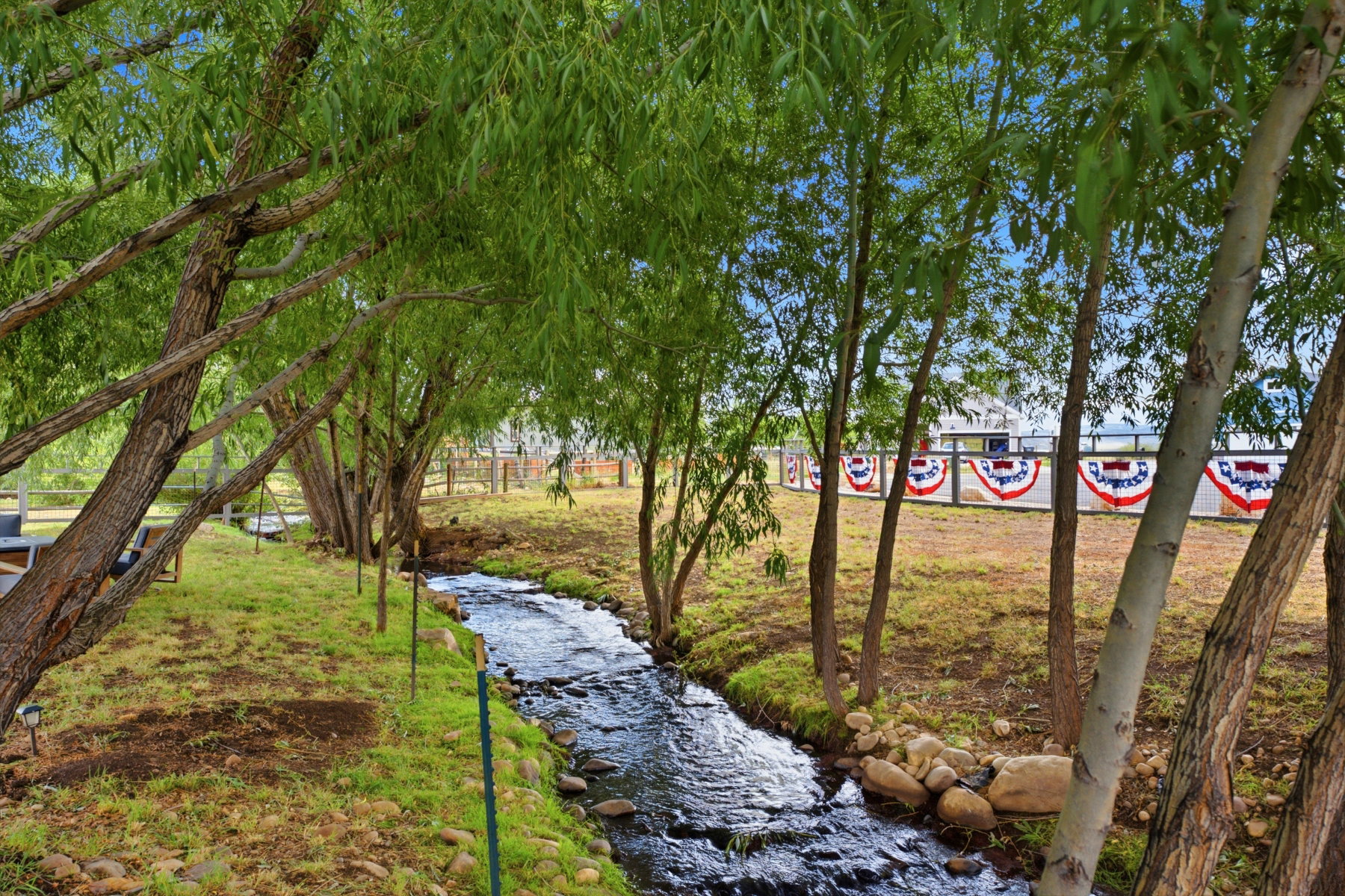 Natural water feature with a stone-lined creek, surrounded by mature trees and verdant ground cover