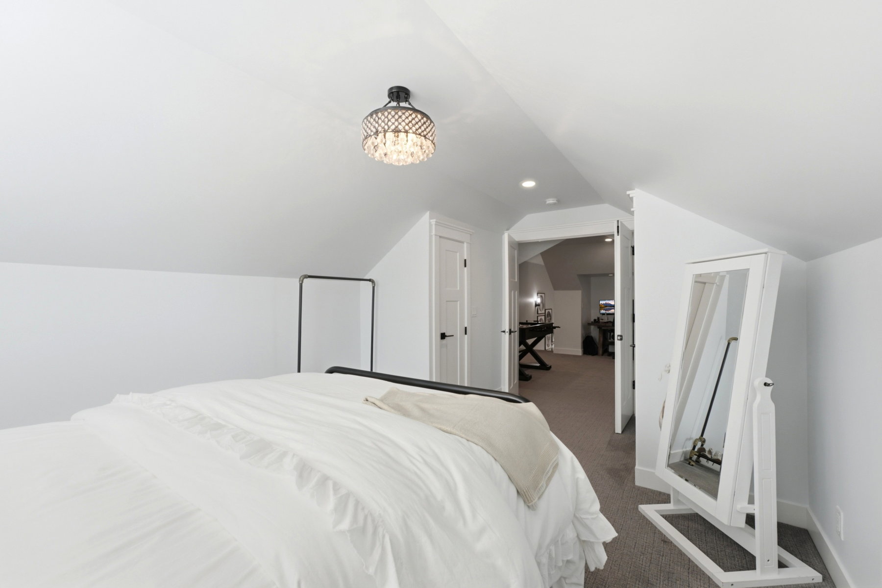 Sloped ceiling room featuring a crystal chandelier, recessed lighting, and white paneled doors with dark hardware
