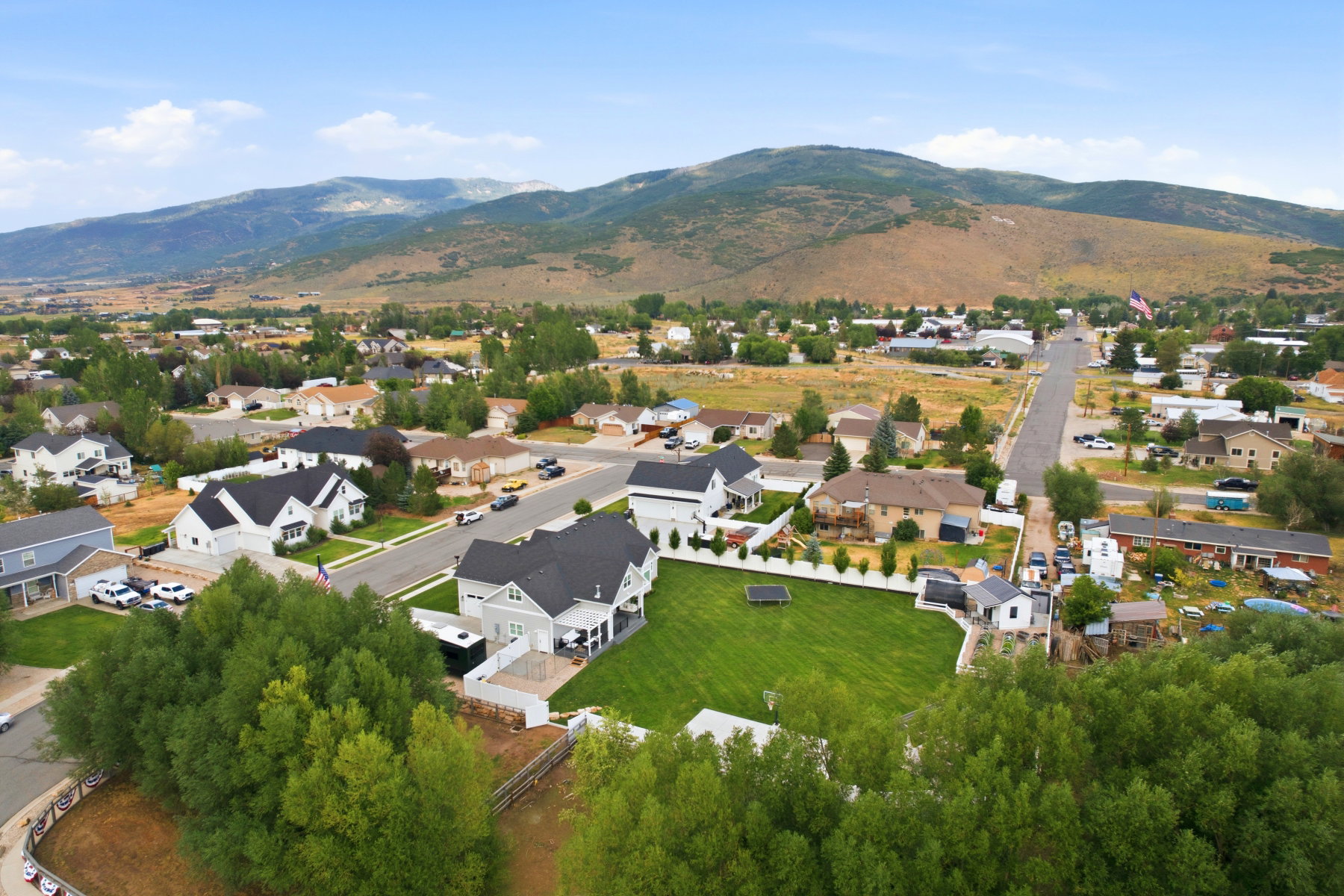 Spacious property featuring a large green lawn, white fencing, and mature trees