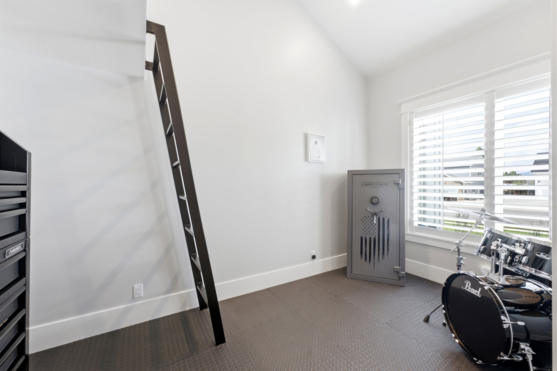 Room featuring an angled ceiling, white walls, and dark-toned flooring