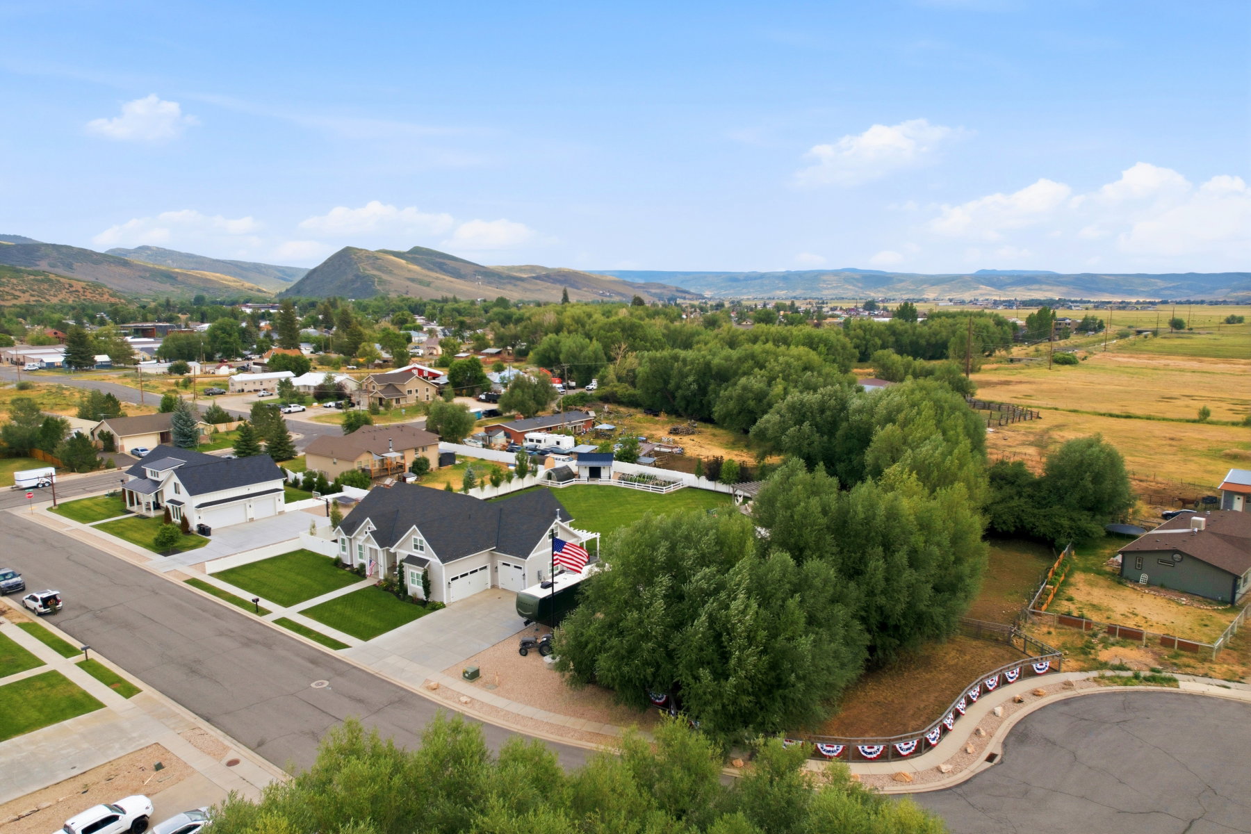 Expansive aerial view showcasing a modern light-colored residence with a dark roof