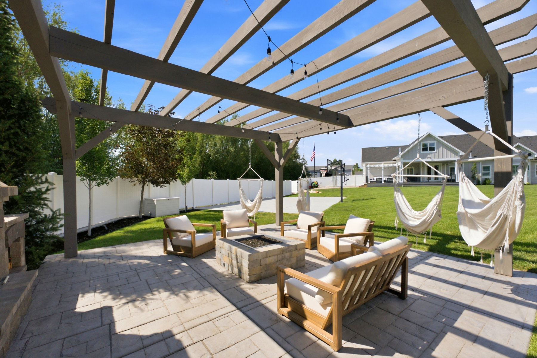 Spacious stamped concrete patio with an open pergola, integrated fire pit, and stone-clad outdoor fireplace structure