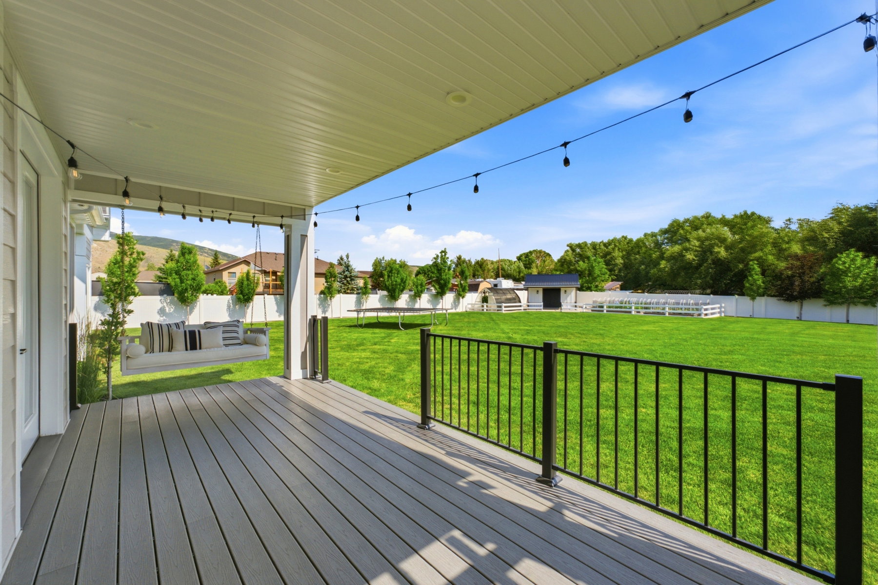 Spacious covered deck featuring composite decking and a black metal railing