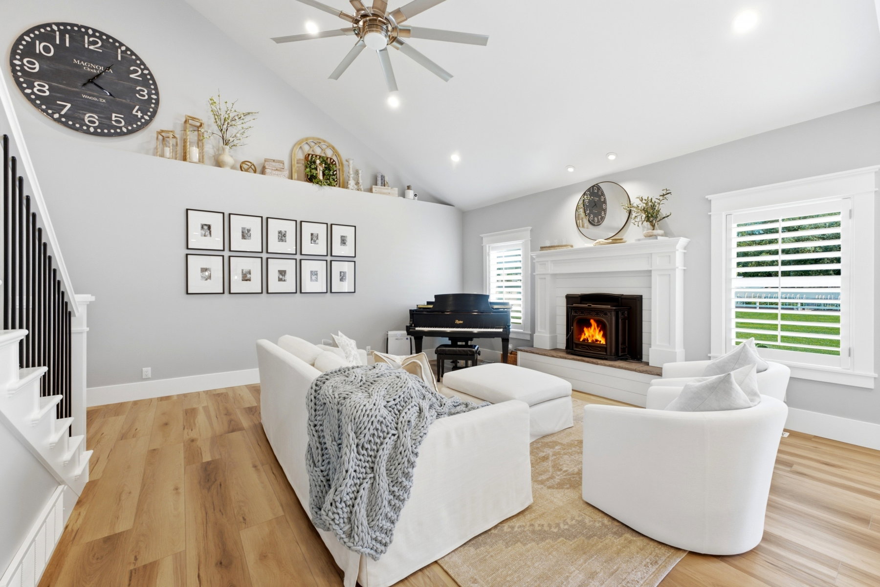 Living area featuring vaulted ceilings, a central fireplace with a white mantel, and wood-finish flooring