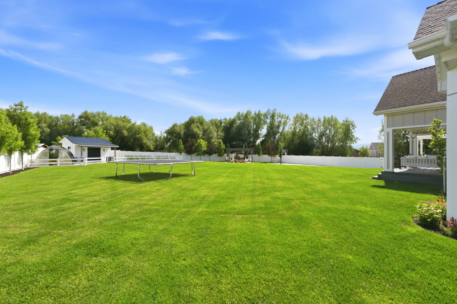 Expansive green lawn with a white privacy fence