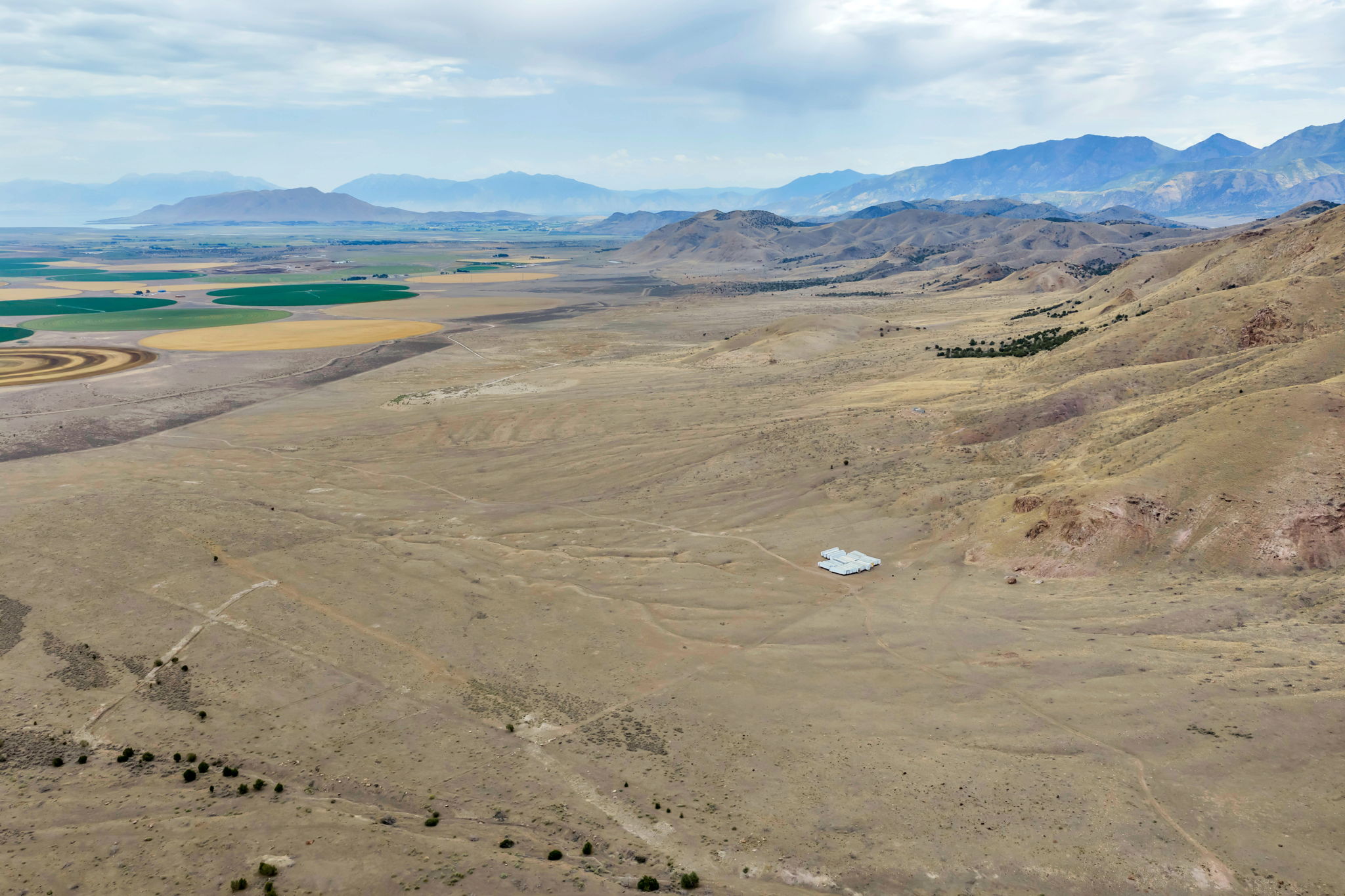Expansive arid landscape featuring distant mountains and agricultural circles