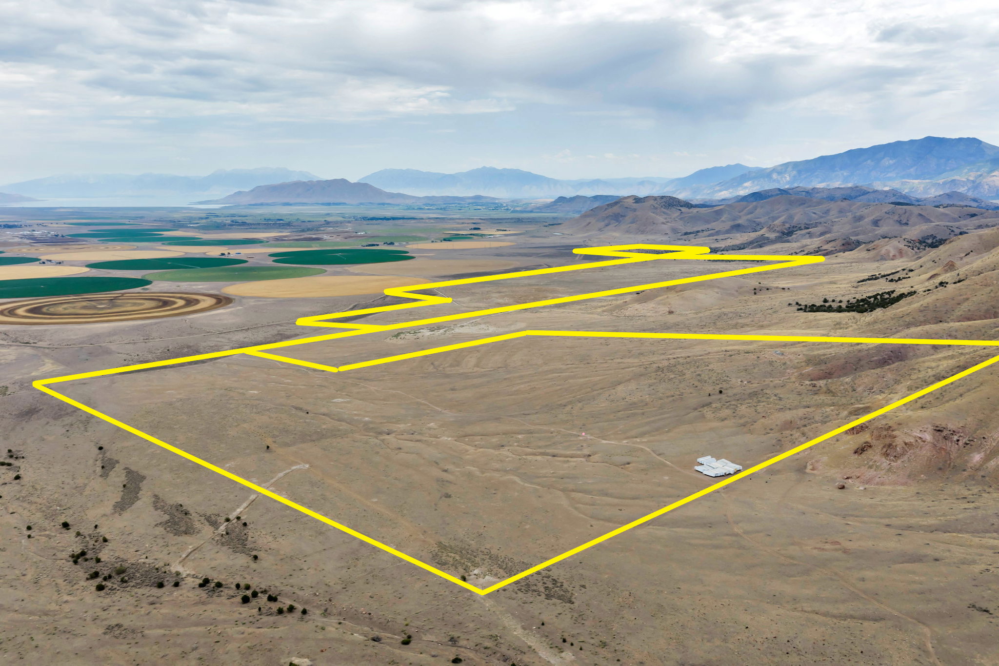 Expansive land parcel with defined boundaries, featuring varied terrain including rolling hills and flat areas