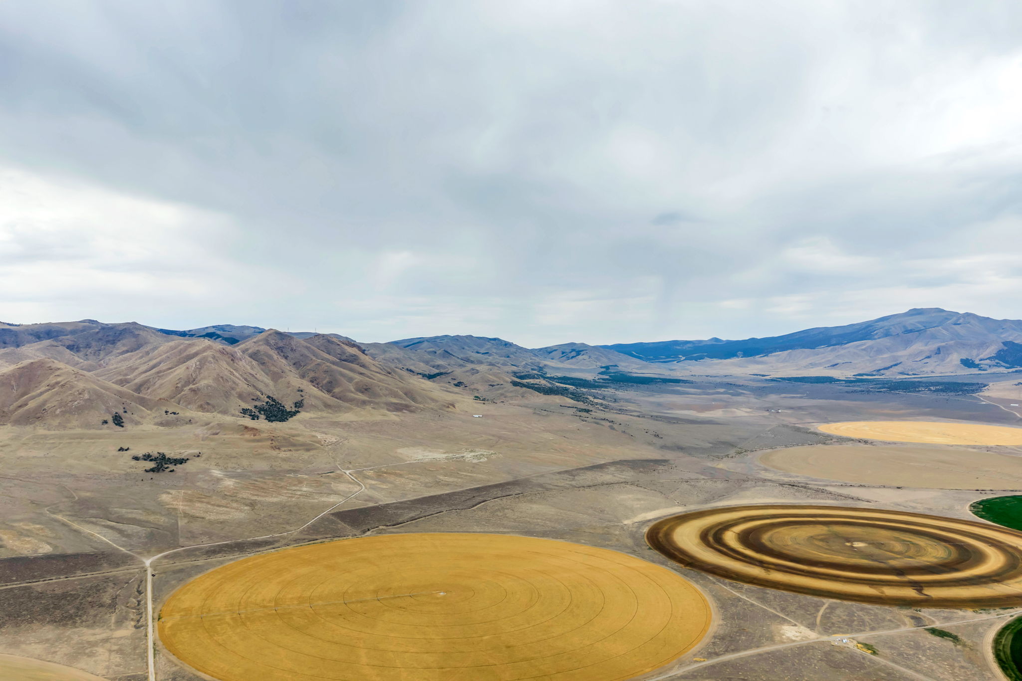Expansive agricultural landscape featuring circular fields, mountainous terrain, and open undeveloped land