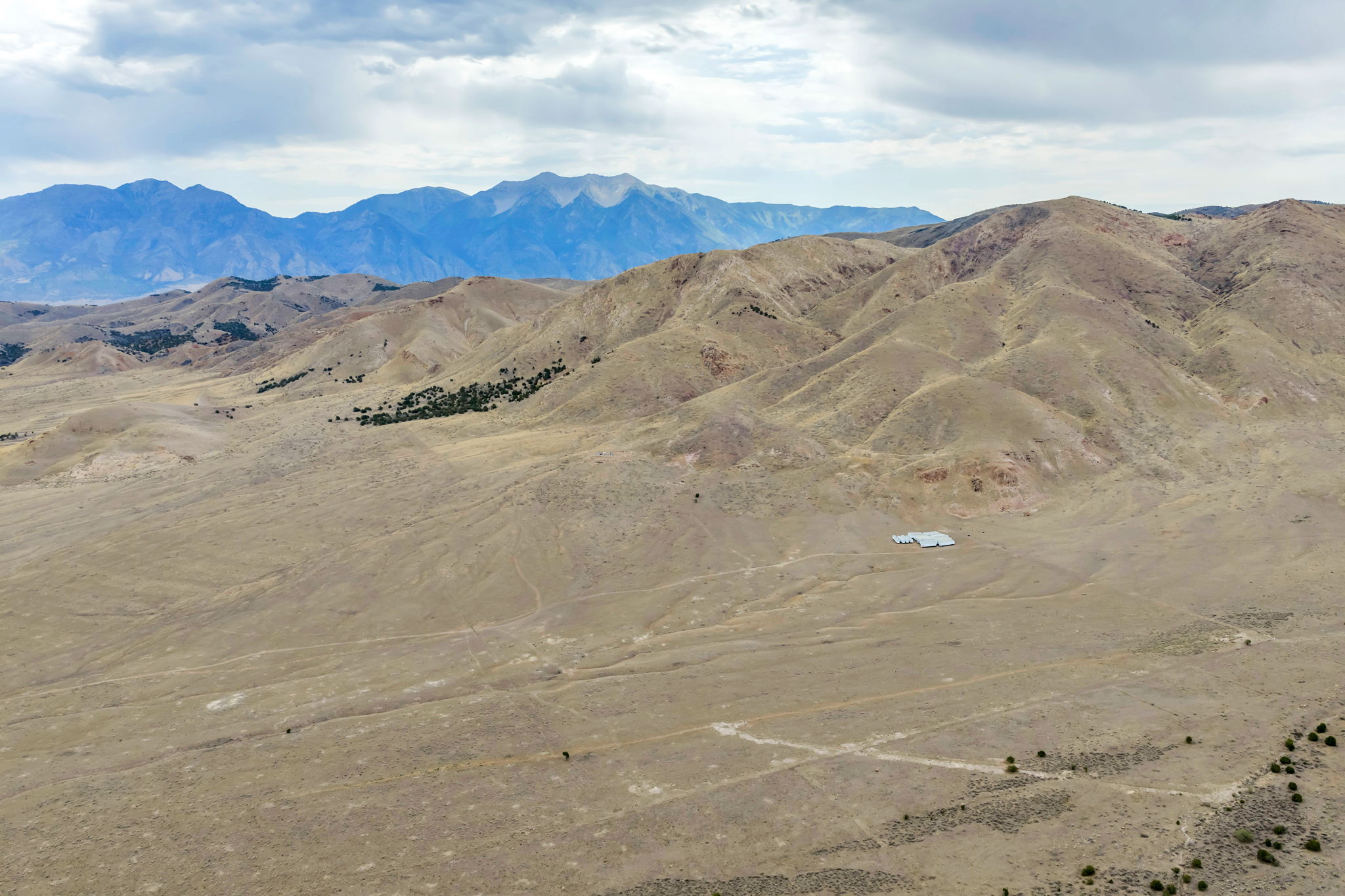 Expansive arid landscape featuring distant blue mountains and rolling hills
