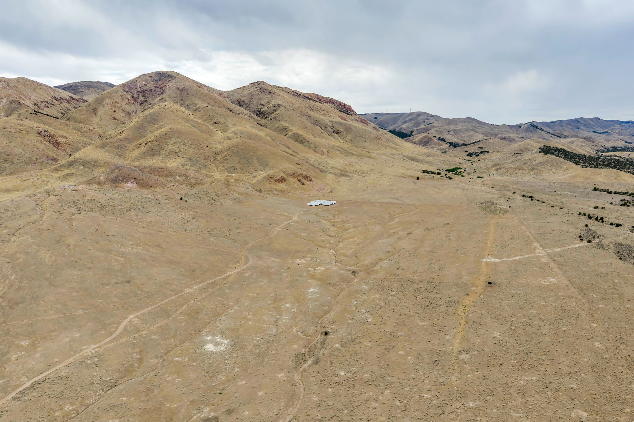 Expansive land parcel featuring distant mountain ranges and a solitary structure
