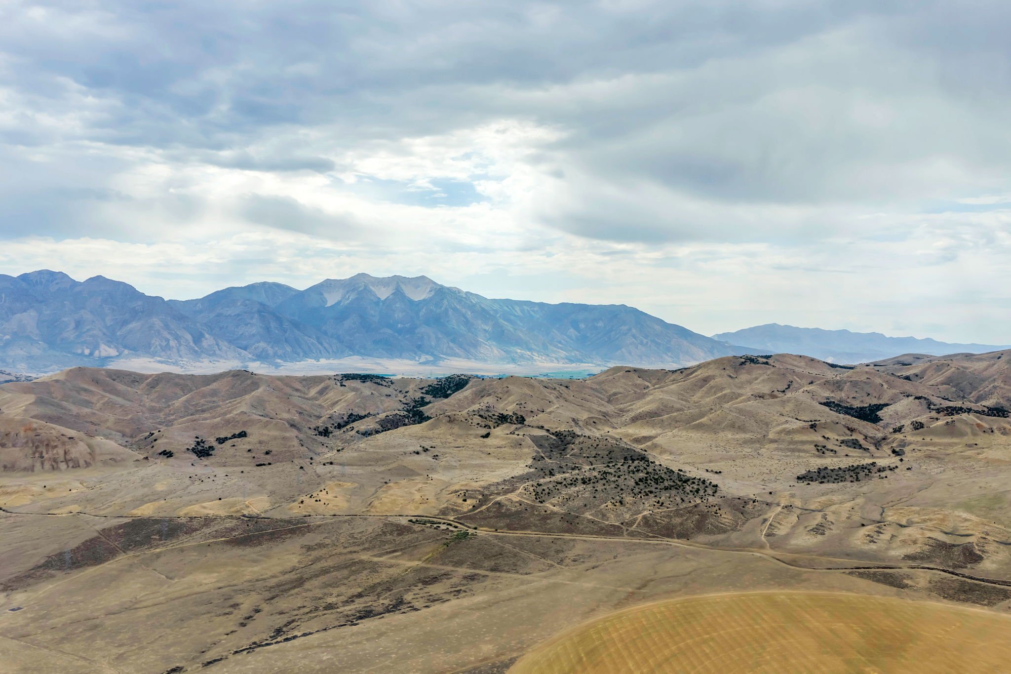 Expansive desert landscape featuring rolling hills and distant mountains under a cloudy sky