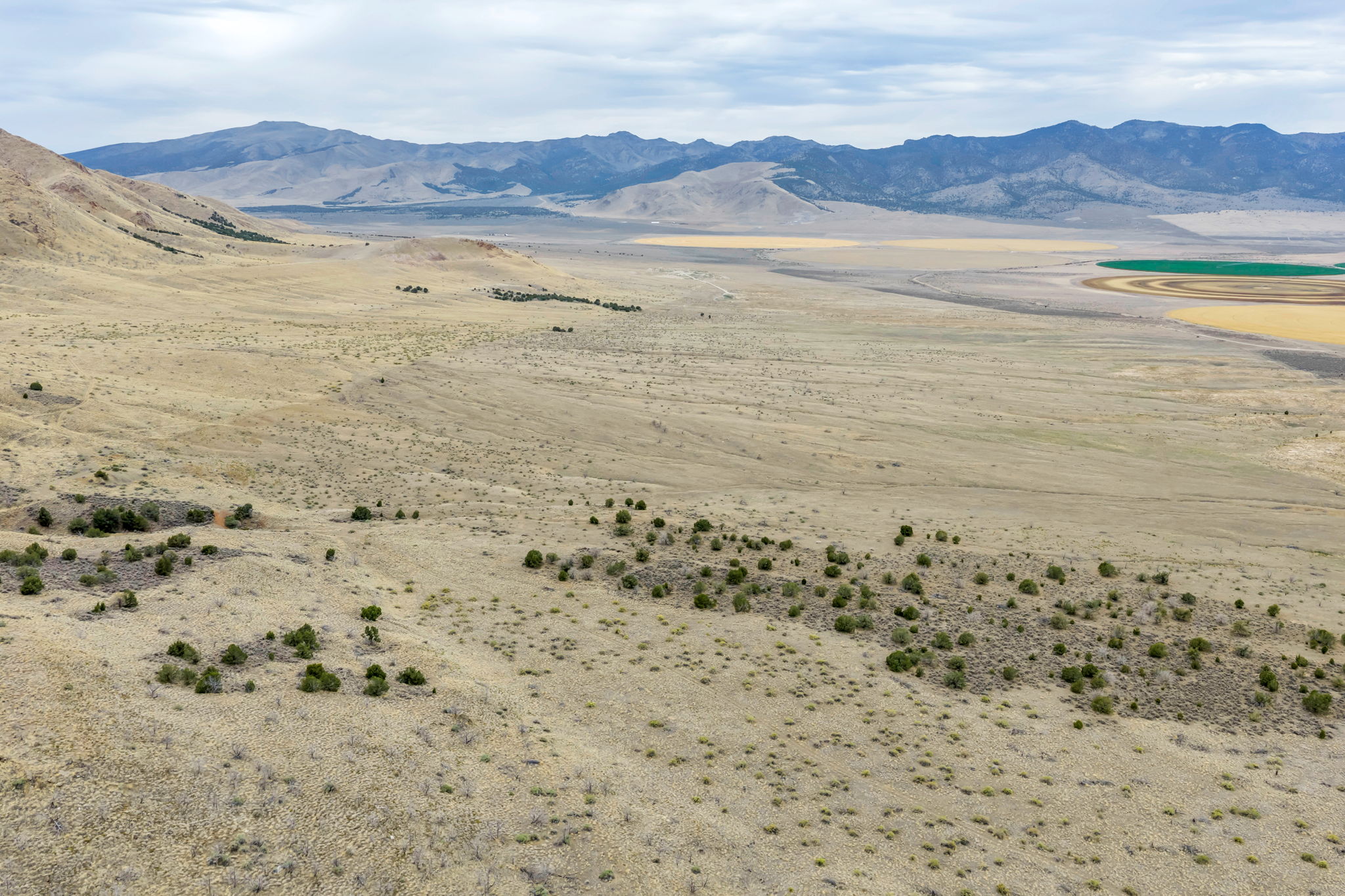 Expansive land parcel featuring natural desert vegetation, rolling hills, and distant mountain ranges