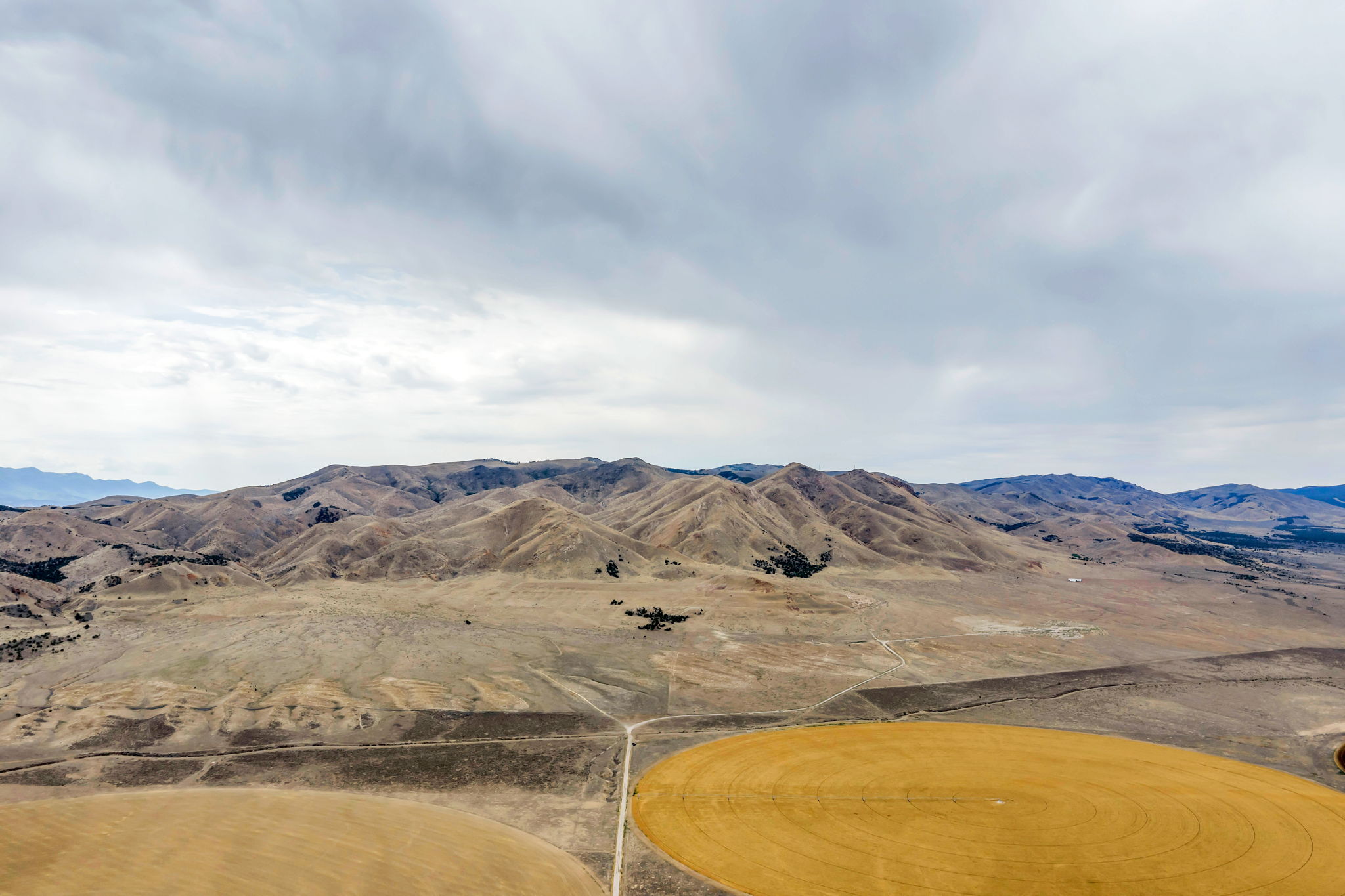 Expansive rural landscape featuring a mountainous backdrop and visible agricultural fields