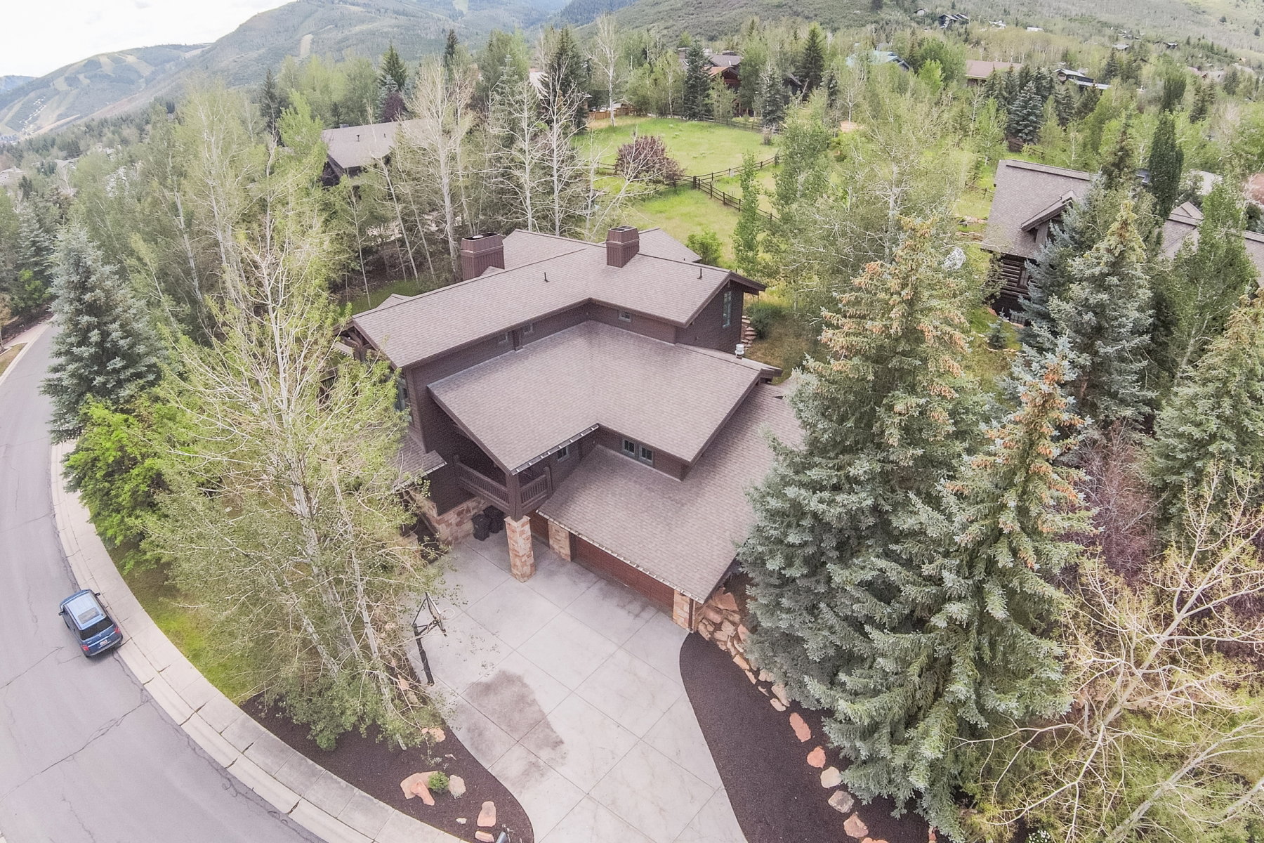 Multi-level residence featuring a brown shingle roof, stone accents, and an attached two-car garage