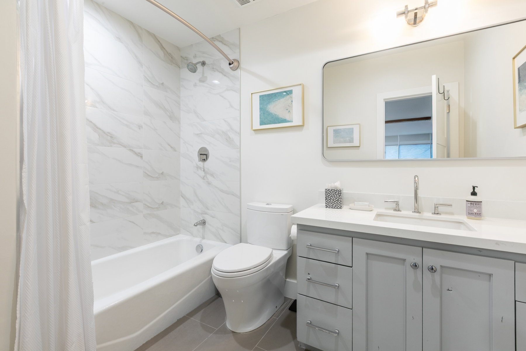 Bathroom featuring a single vanity with light grey cabinetry, a solid surface countertop, and an undermount sink
