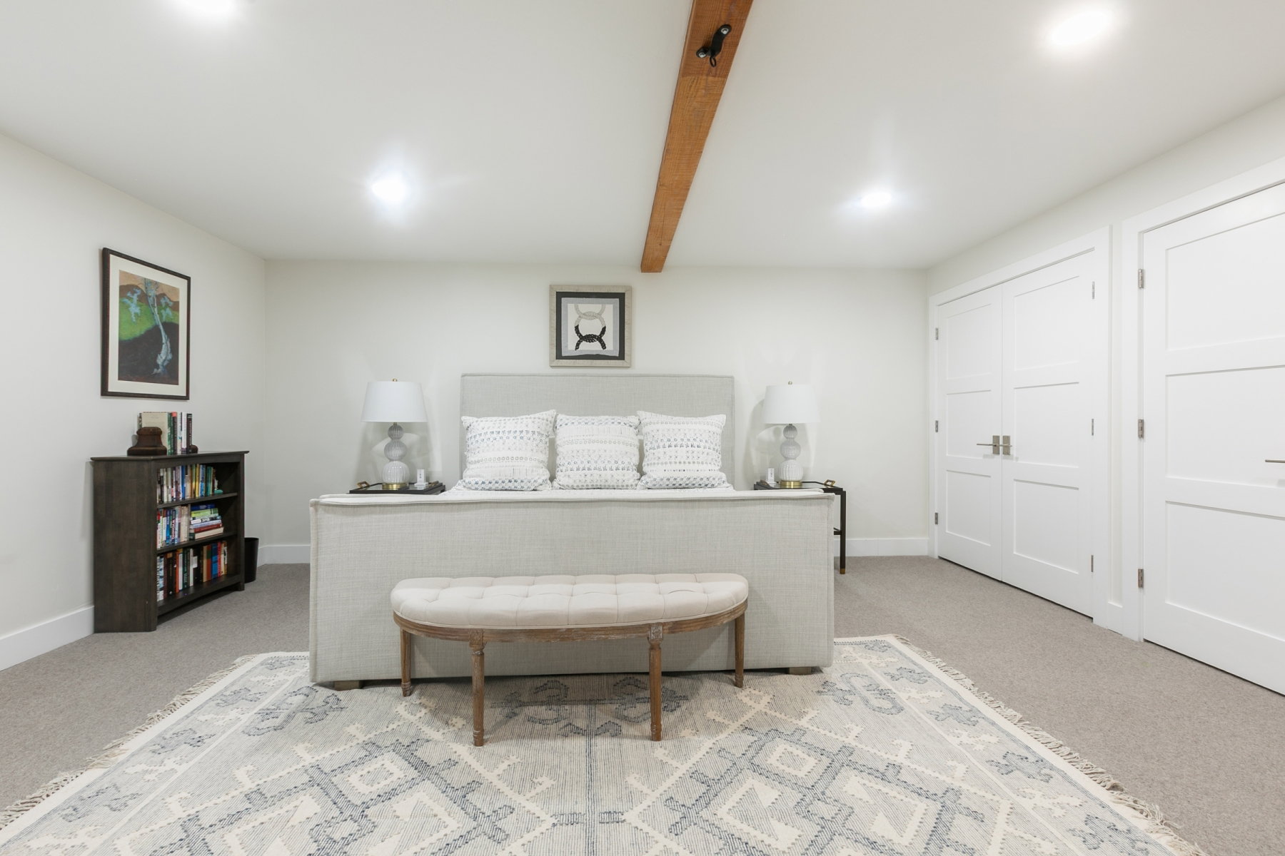 Spacious room featuring neutral carpeting, recessed ceiling lighting, a prominent wood beam accent, and two panel doors with modern hardware