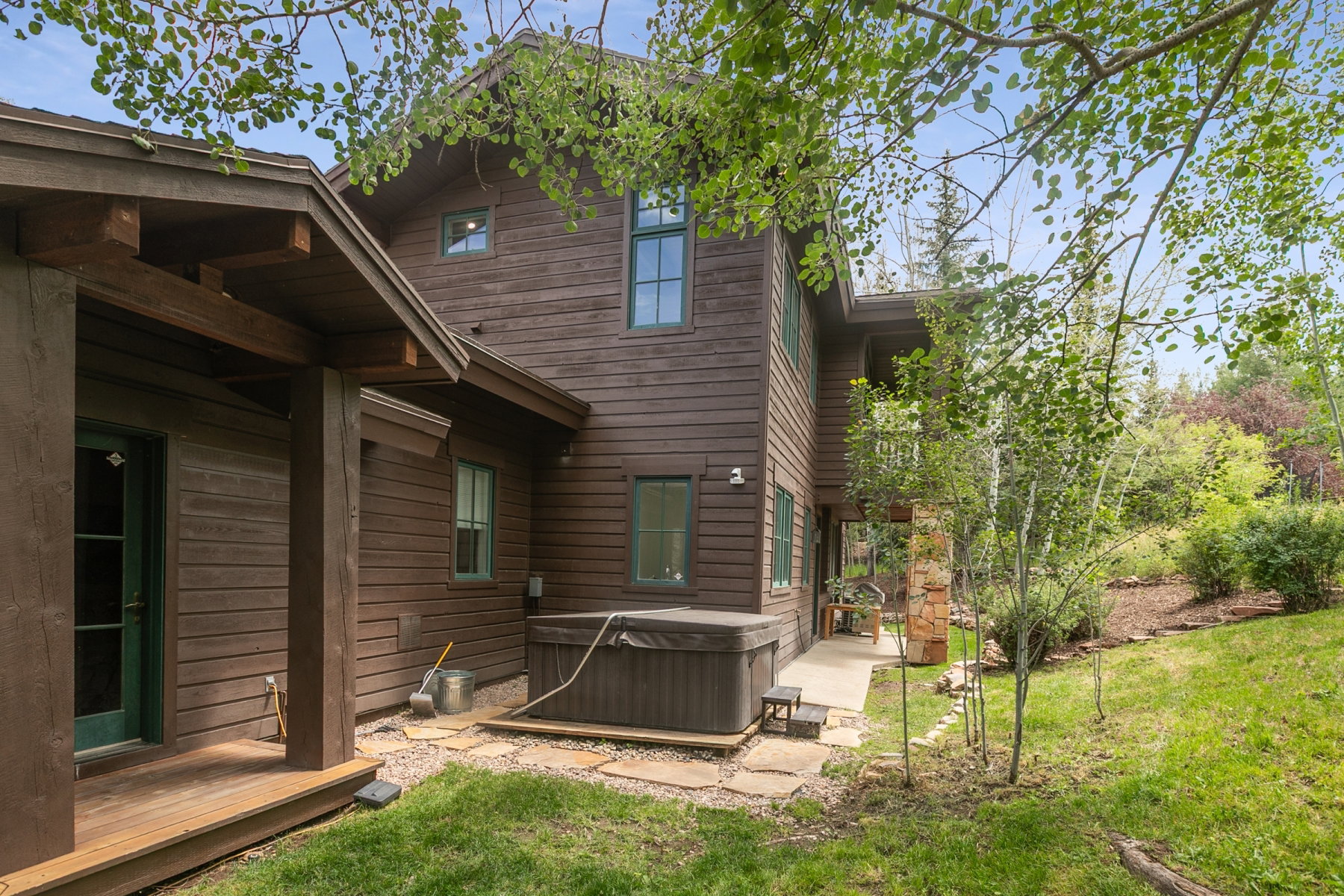 Multi-level exterior featuring dark wood-finish siding, green trim windows, and a covered porch
