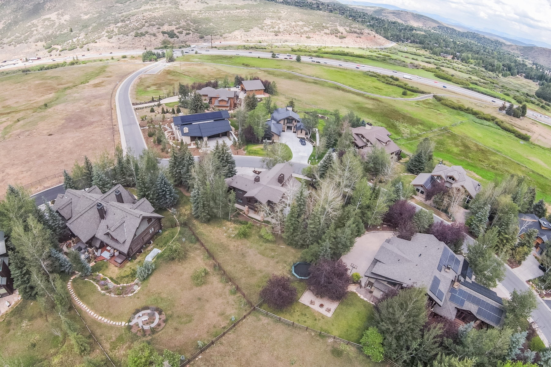 Expansive property featuring a multi-story residence with a prominent gabled roof and surrounding mature trees