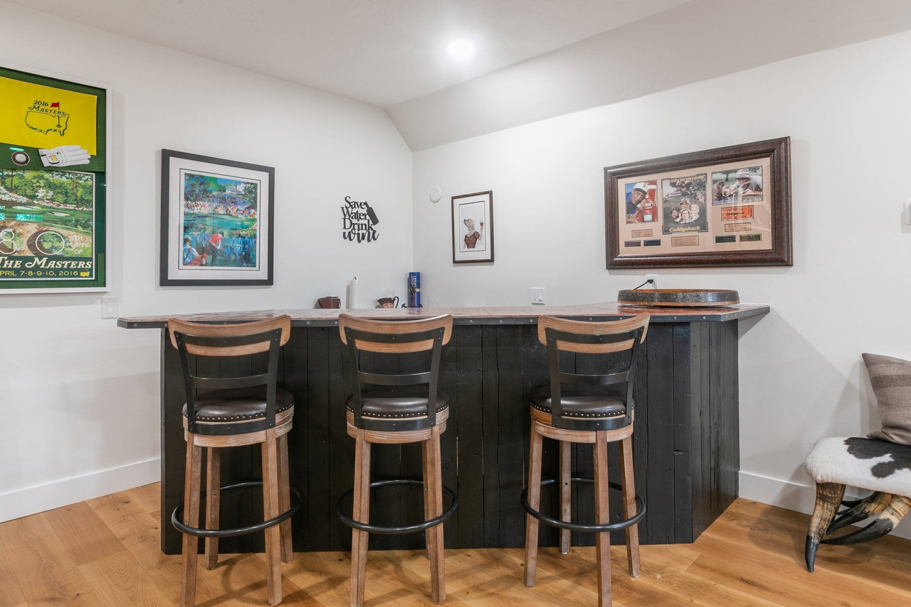 Built-in bar with a dark wood-finish base, contrasting light wood-finish countertop, and wood-finish flooring