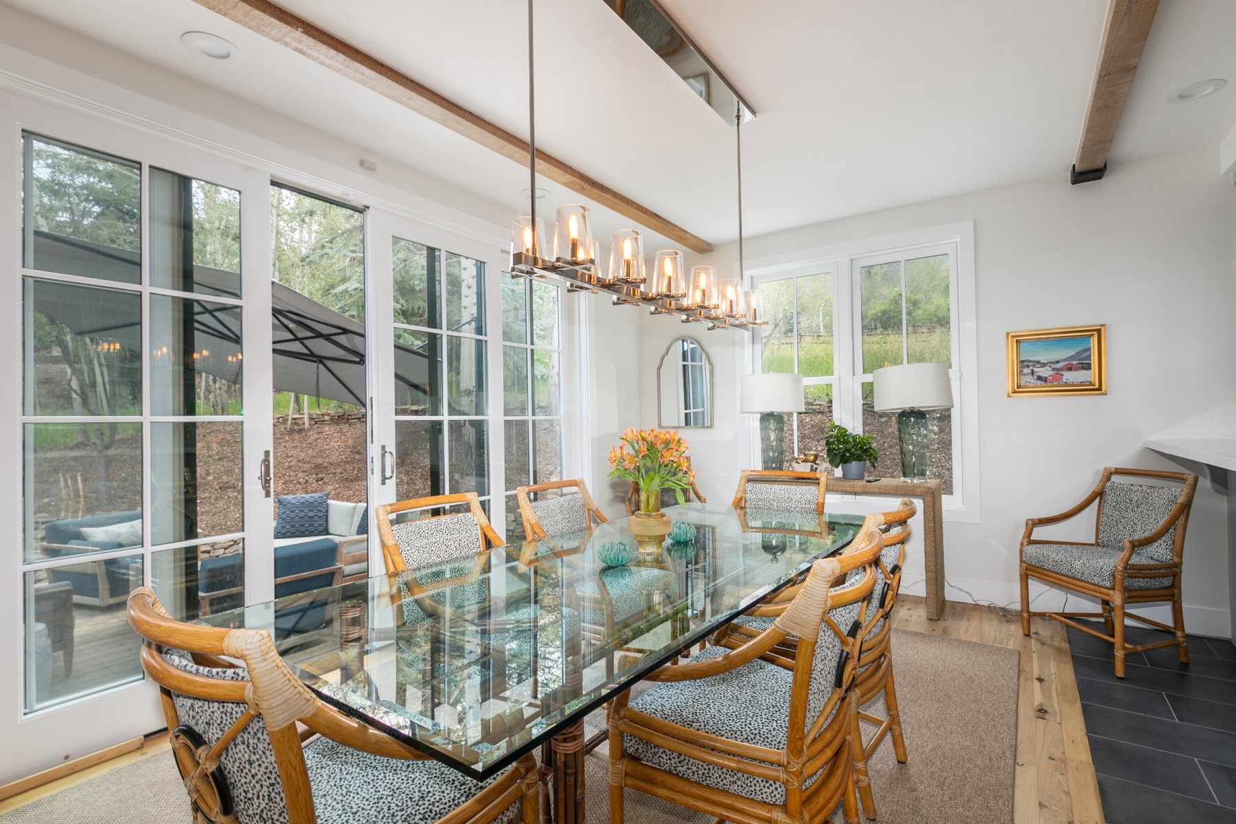 Dining area with exposed wood ceiling beams, a multi-light linear chandelier, and wide plank wood-finish flooring