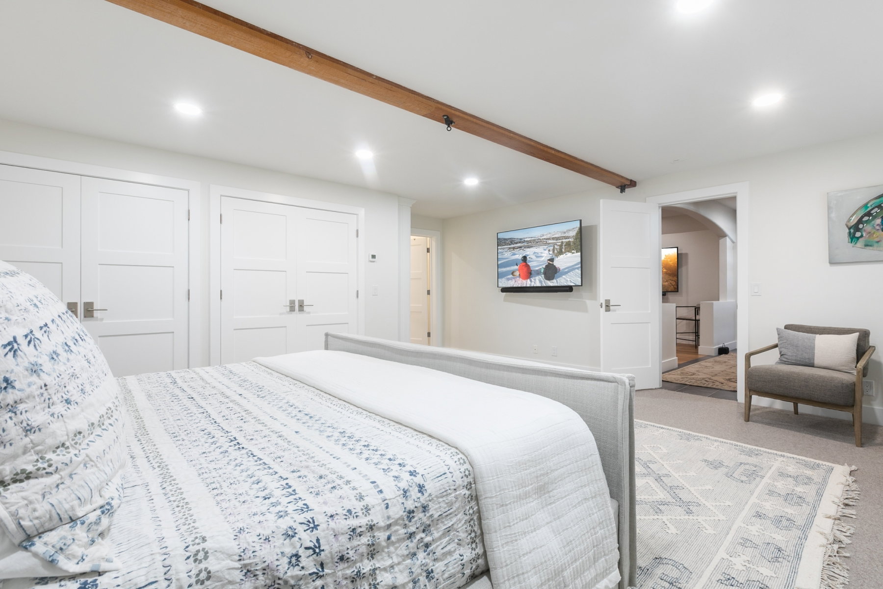 Recessed lighting illuminates a space featuring a wood beam accent