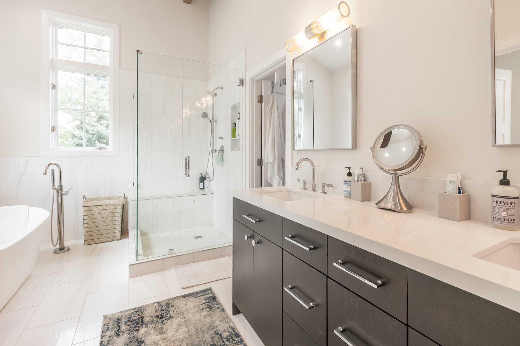 Contemporary bathroom featuring a dual vanity with dark cabinetry and light countertops