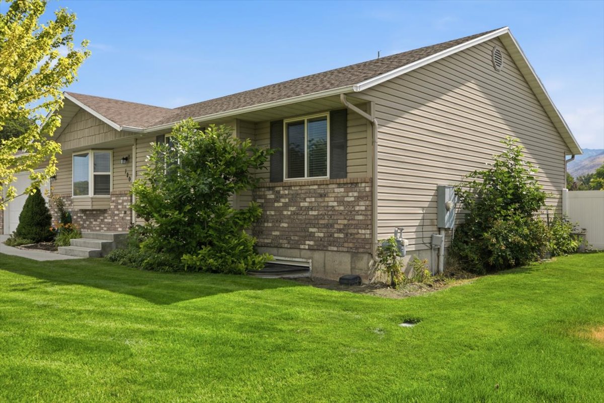 Exterior featuring tan siding, brick accents, and a gabled roof