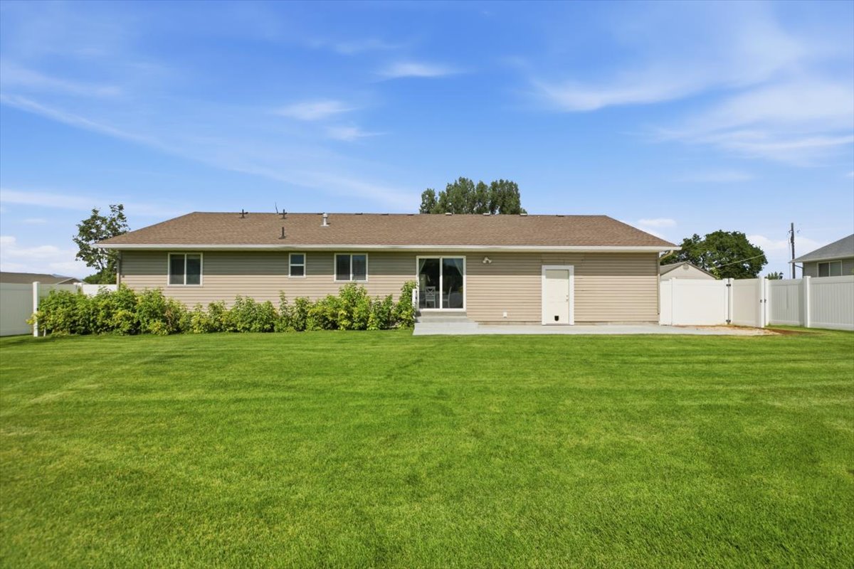Spacious rear yard featuring an expansive lawn, a concrete patio, and a privacy fence