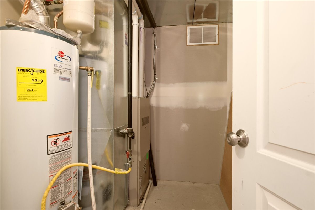 Utility area featuring a water heater, furnace system, ductwork, and vent