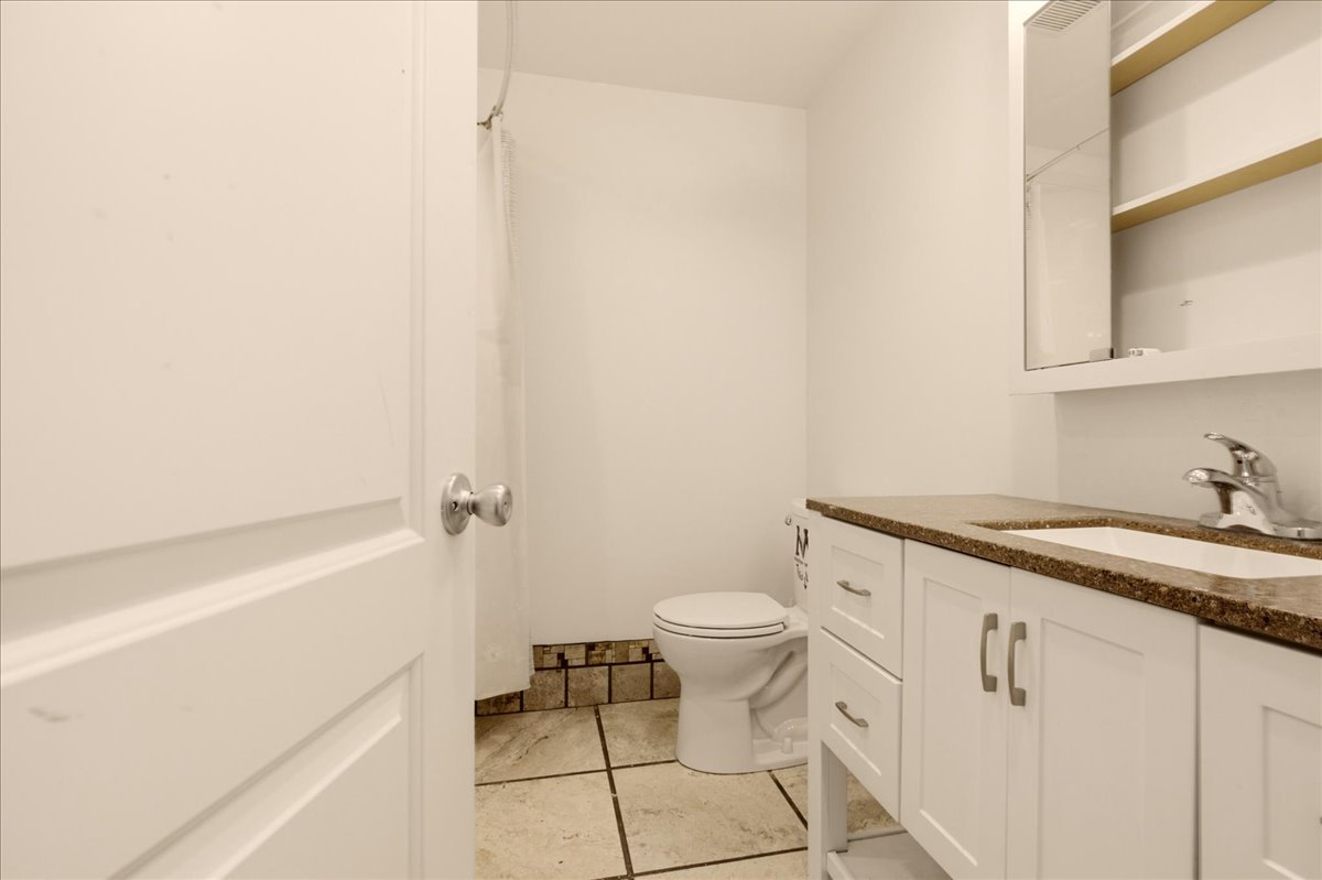Bathroom featuring a white vanity with a brown speckled countertop, an undermount sink, and chrome fixtures