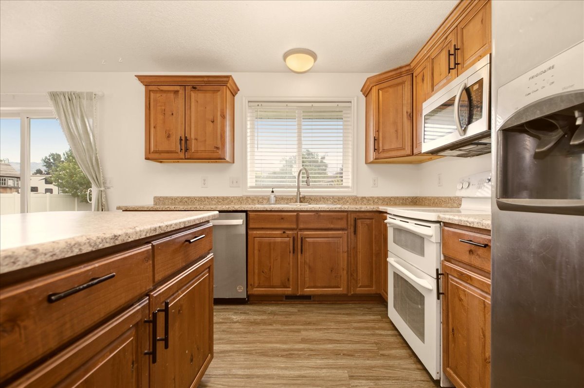 Kitchen featuring wood-finish cabinetry, light-toned countertops, and wood-finish flooring