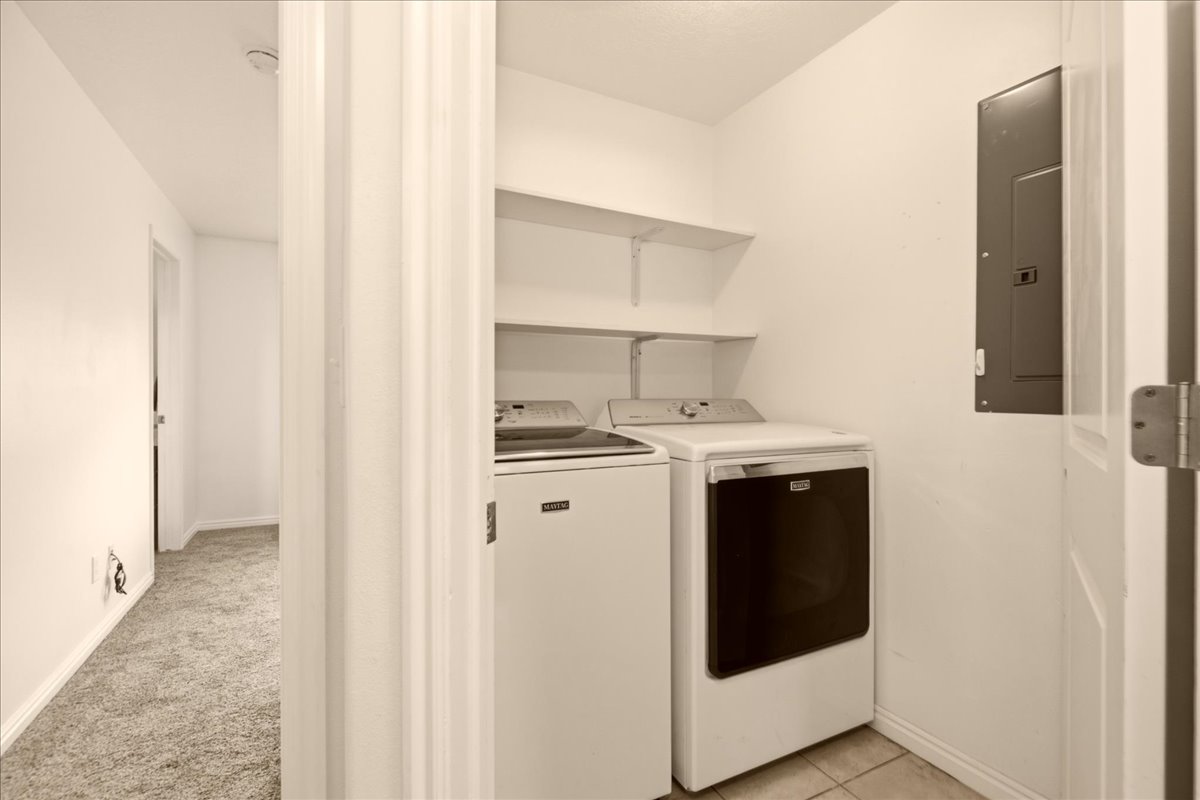 Dedicated laundry area featuring tiled flooring and integrated shelving