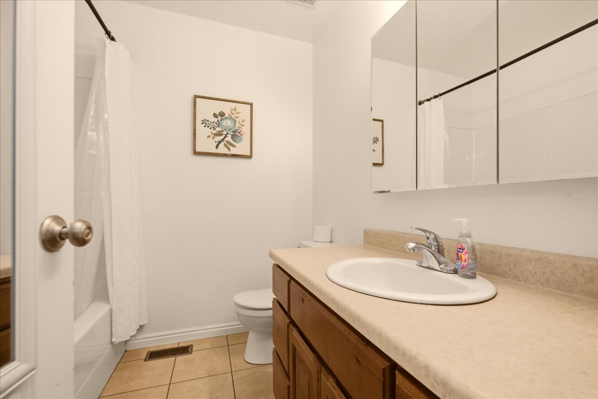 Bathroom featuring a wood-finish vanity with an integrated sink and light-toned countertop